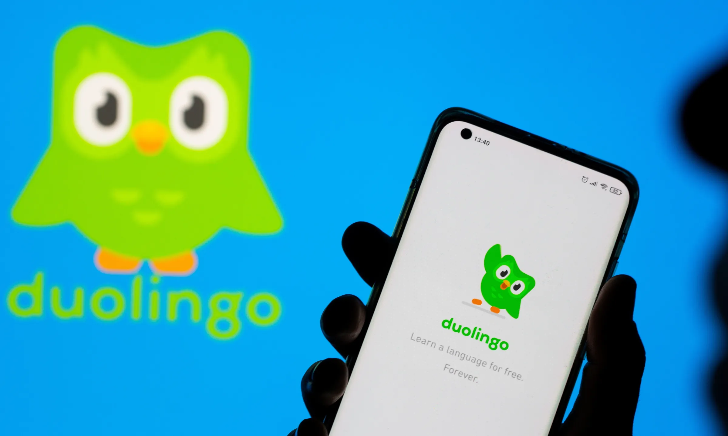 Woman with her smartphone poses in front of displayed Duolingo logo in this illustration taken, June 29, 2021. REUTERS/Dado Ruvic