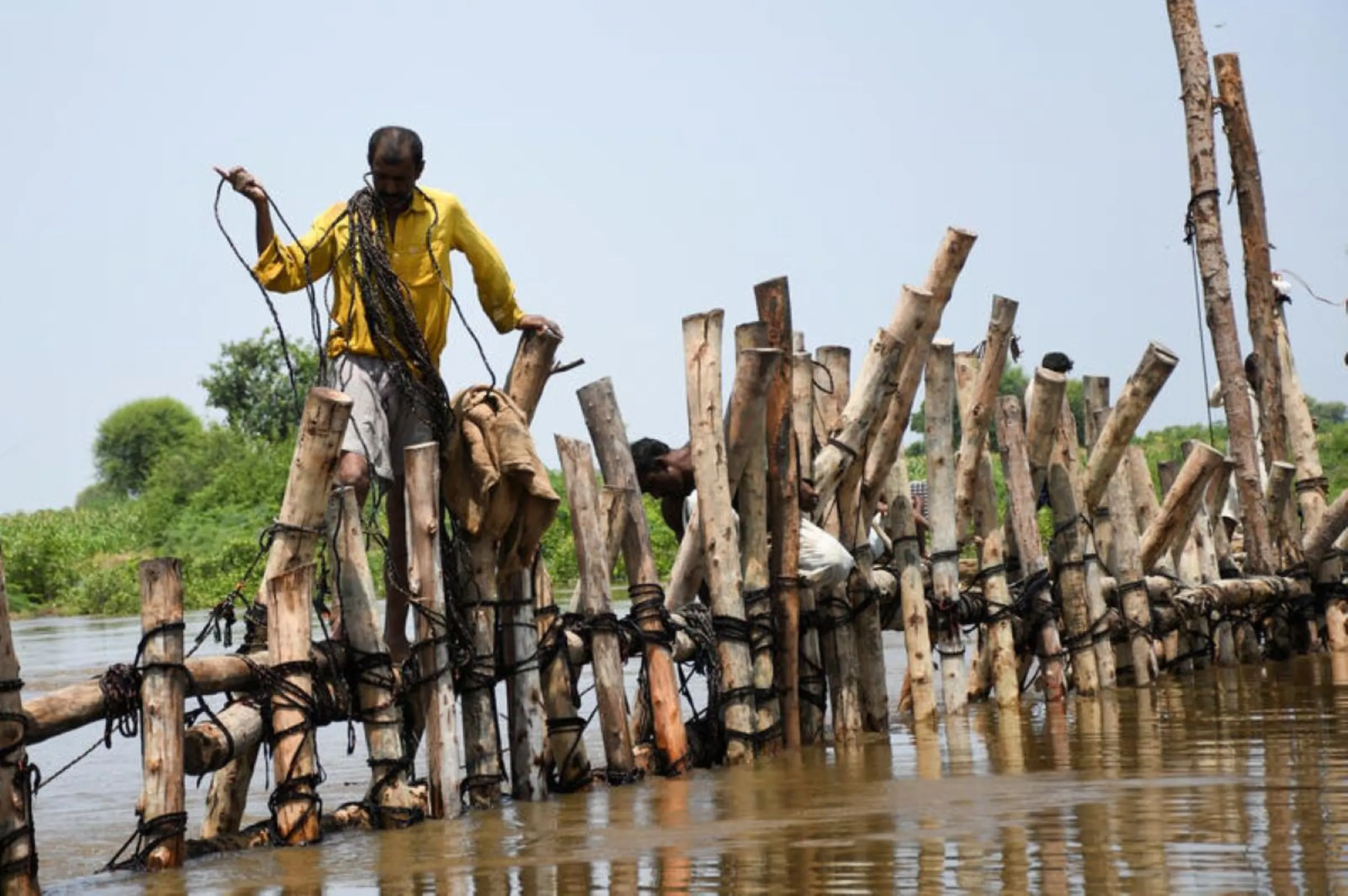 People prepare a barrier with wooden logs and sand bags to stop flood waters during the monsoon season in Puran Dhoro, Badin, Pakistan, August 30, 2022. REUTERS/Yasir Rajput 