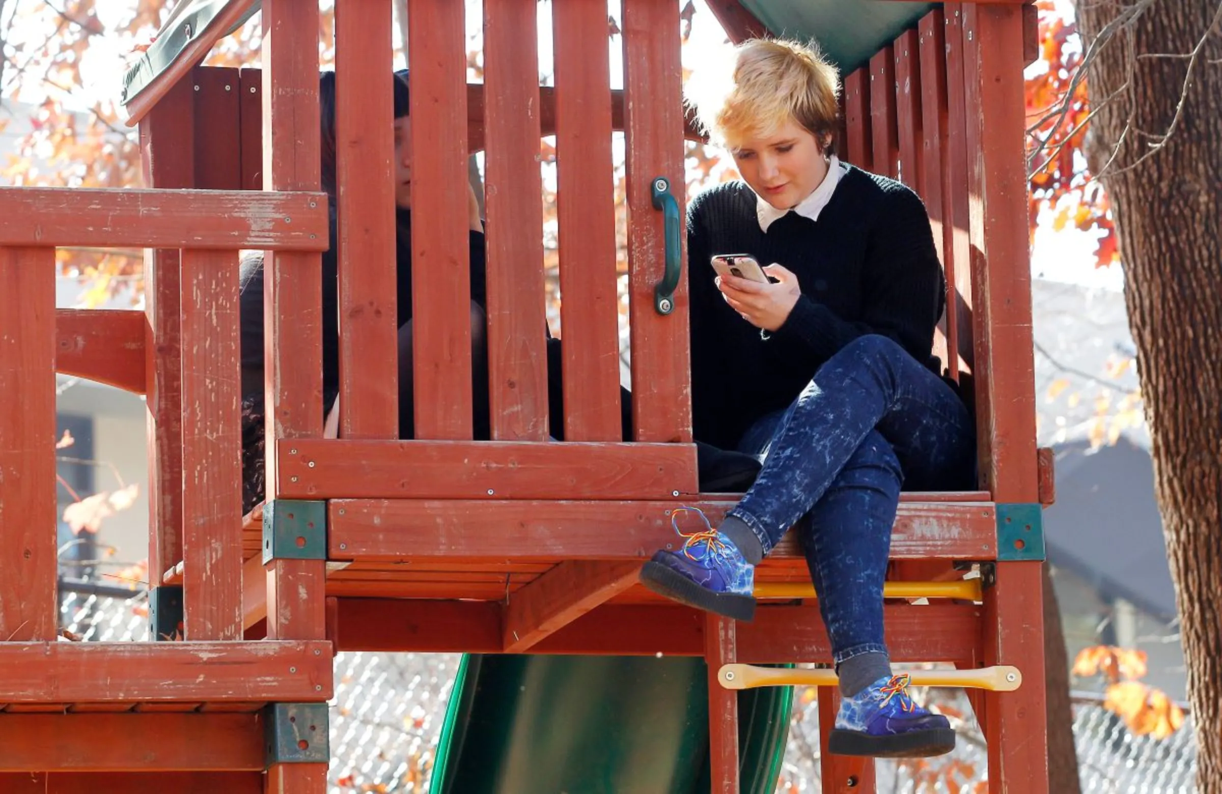 A student checks her phone during lunch outside in a treehouse at a school in Atlanta, Georgia, U.S. on December 7, 2016. REUTERS/Tami Chappell