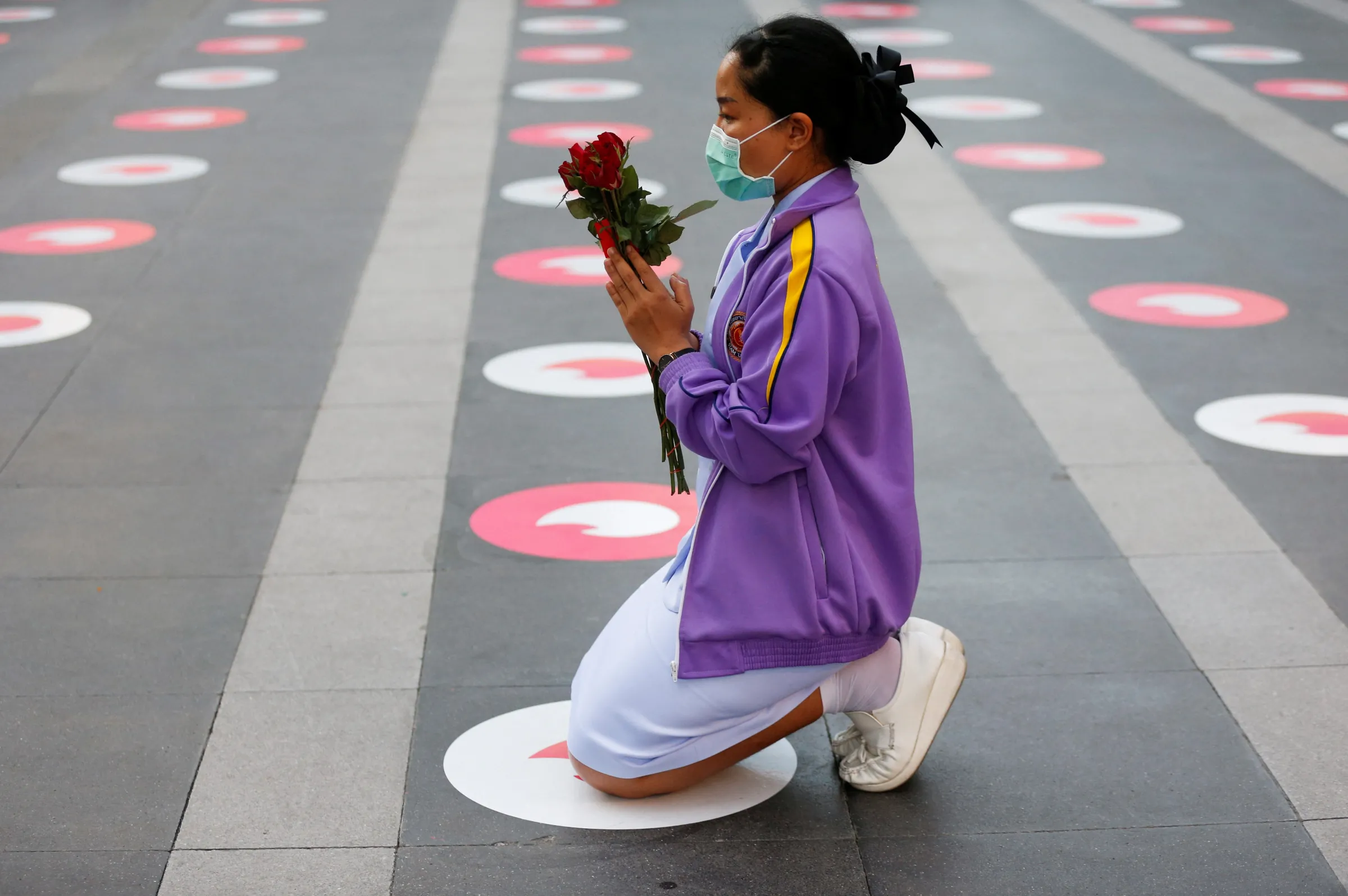 A woman kneels down to pray at a 'Pray and swipe right' event organised by online dating app Tinder, with social-distancing stickers featuring its flame logo on the praying ground, a photo booth where people can take profile pictures for their new accounts, and free offering sets, at the Trimuriti shrine on Valentine's Day in Bangkok, Thailand February 14, 2022