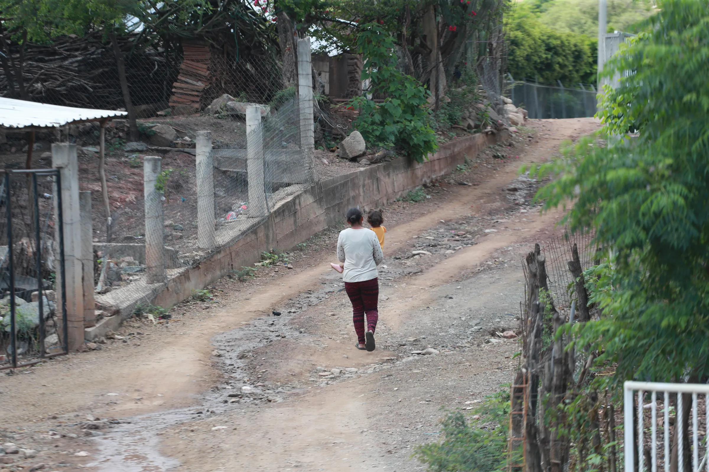 A woman carries a child through the unpaved streets of San Miguel de Las Minas, Puebla, Mexico, September 7, 2022. Thomson Reuters Foundation/Vicente Castillo