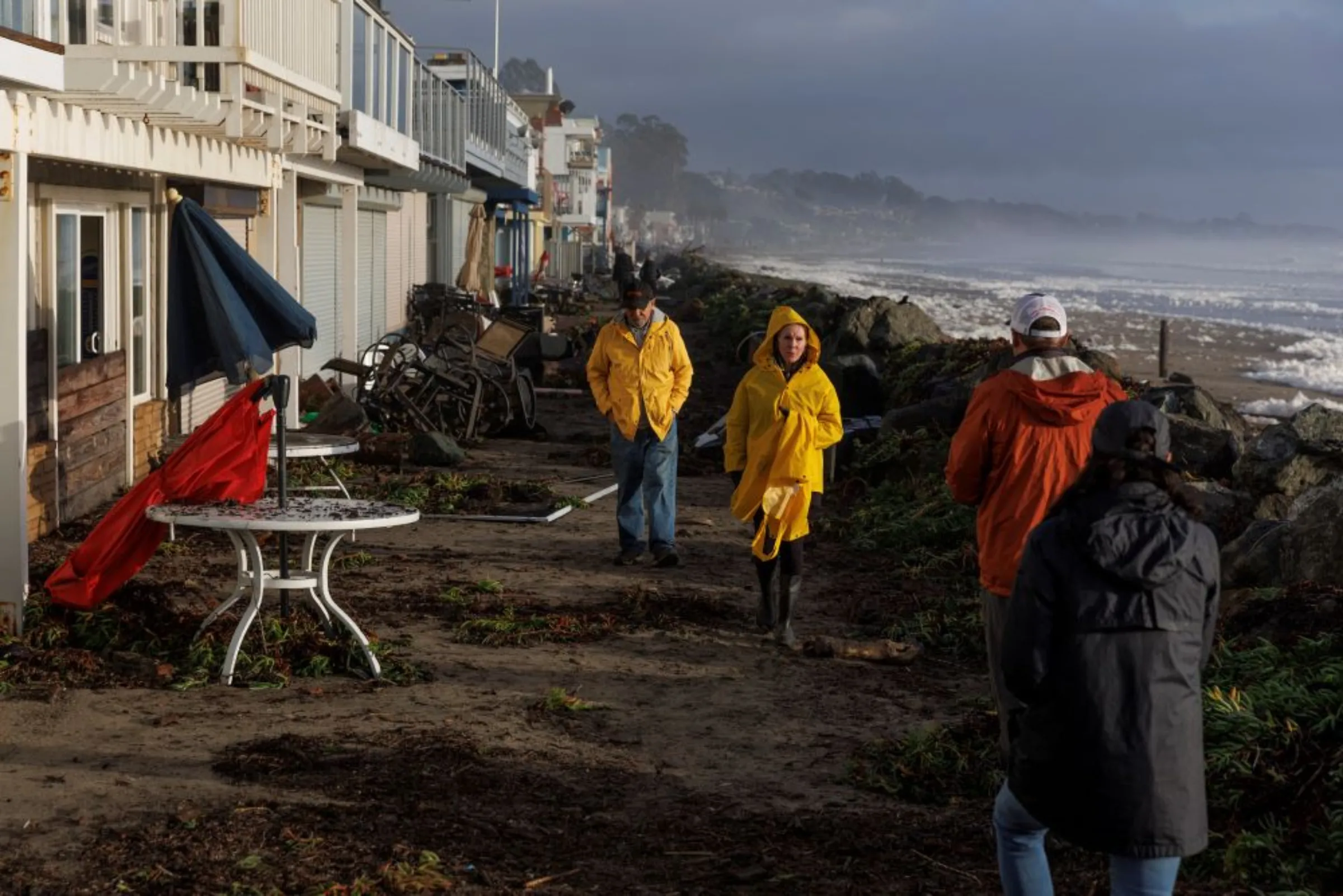 Residents walk along coastal front properties damaged after 'atmospheric river' rainstorms slammed northern California, in the town of Aptos, U.S., January 5, 2023. REUTERS/Carlos Barria