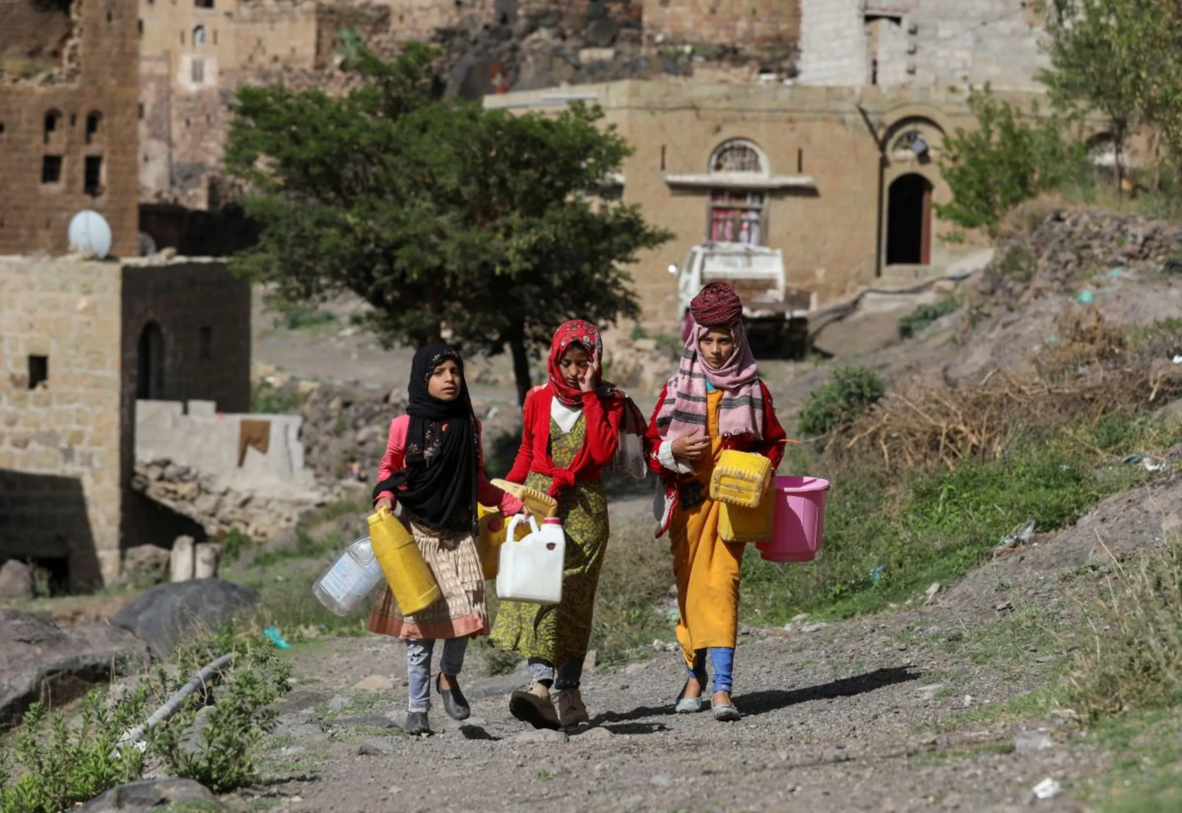 Girls walk as they carry jerrycans to fetch water from a faucet in Bani Matar, Yemen, one of the world's most water-stressed countries, where climate change-induced drought and the lack of sustainable water supplies prevail, August 24, 2023