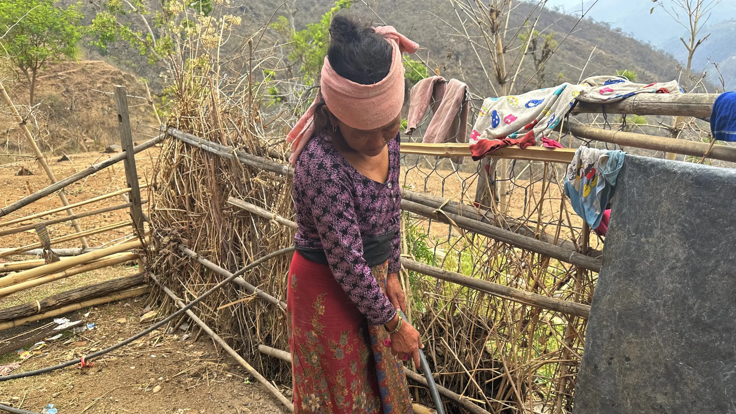 Sarita Rai fills a bucket from water collected in a water harvesting tank in Khotang, Nepal, April 30, 2023