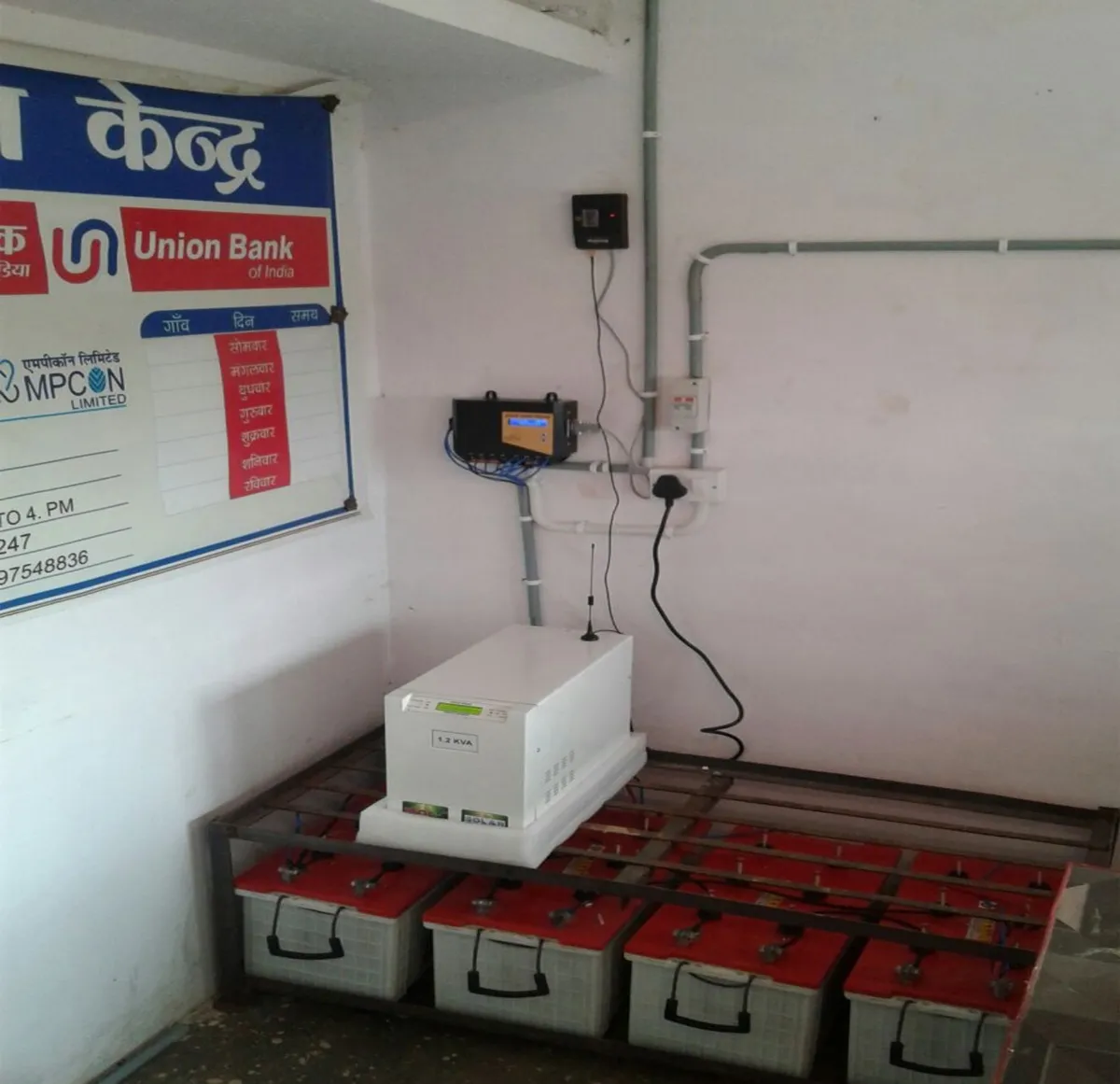 An inverter and battery system is pictured plugged into a wall on top of shelving