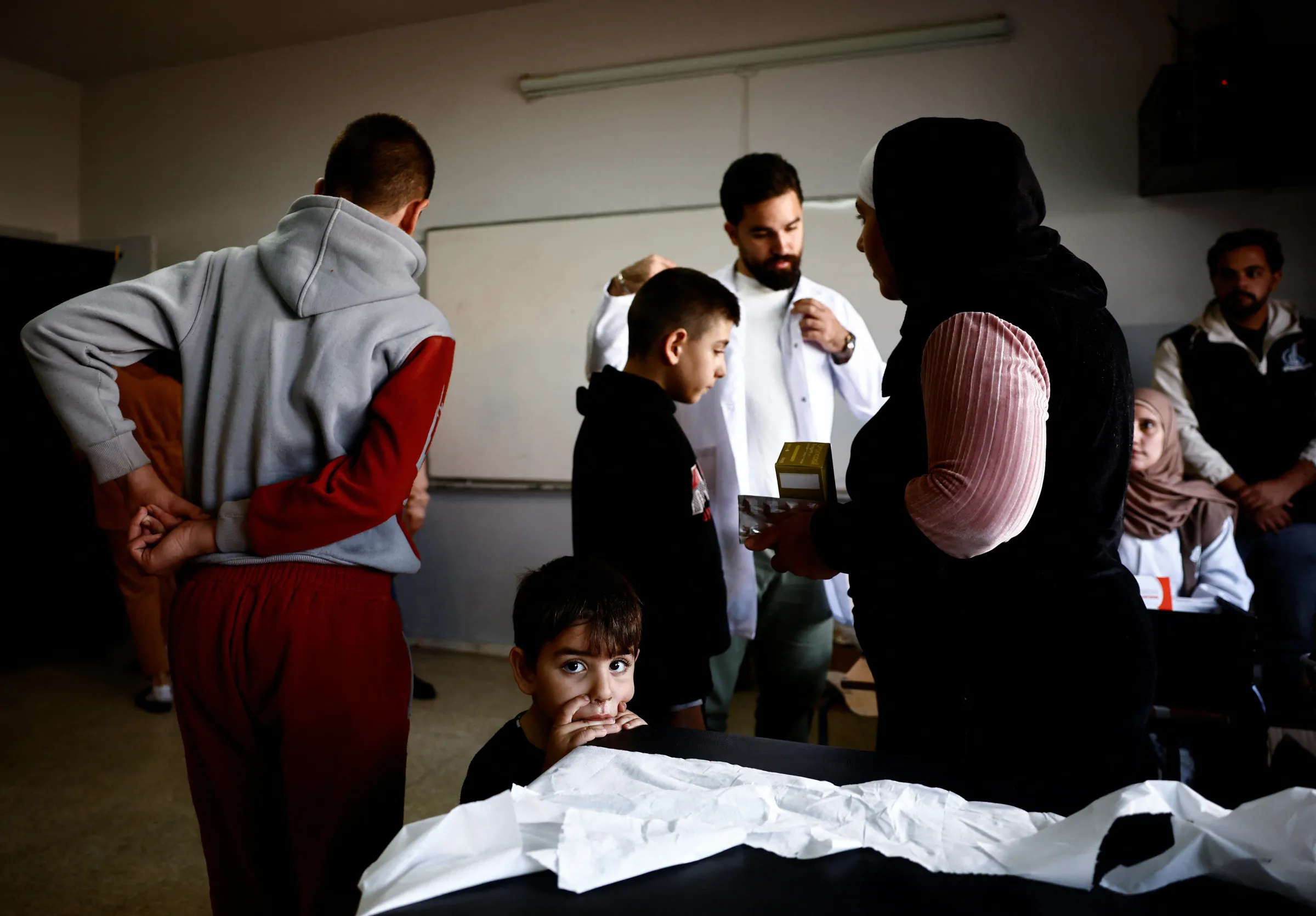 A child looks on as displaced people wait to have a medical check-up at a clinic in a school turned into a shelter in the West Bekaa, Lebanon, November 7, 2024. REUTERS/Yara Nardi