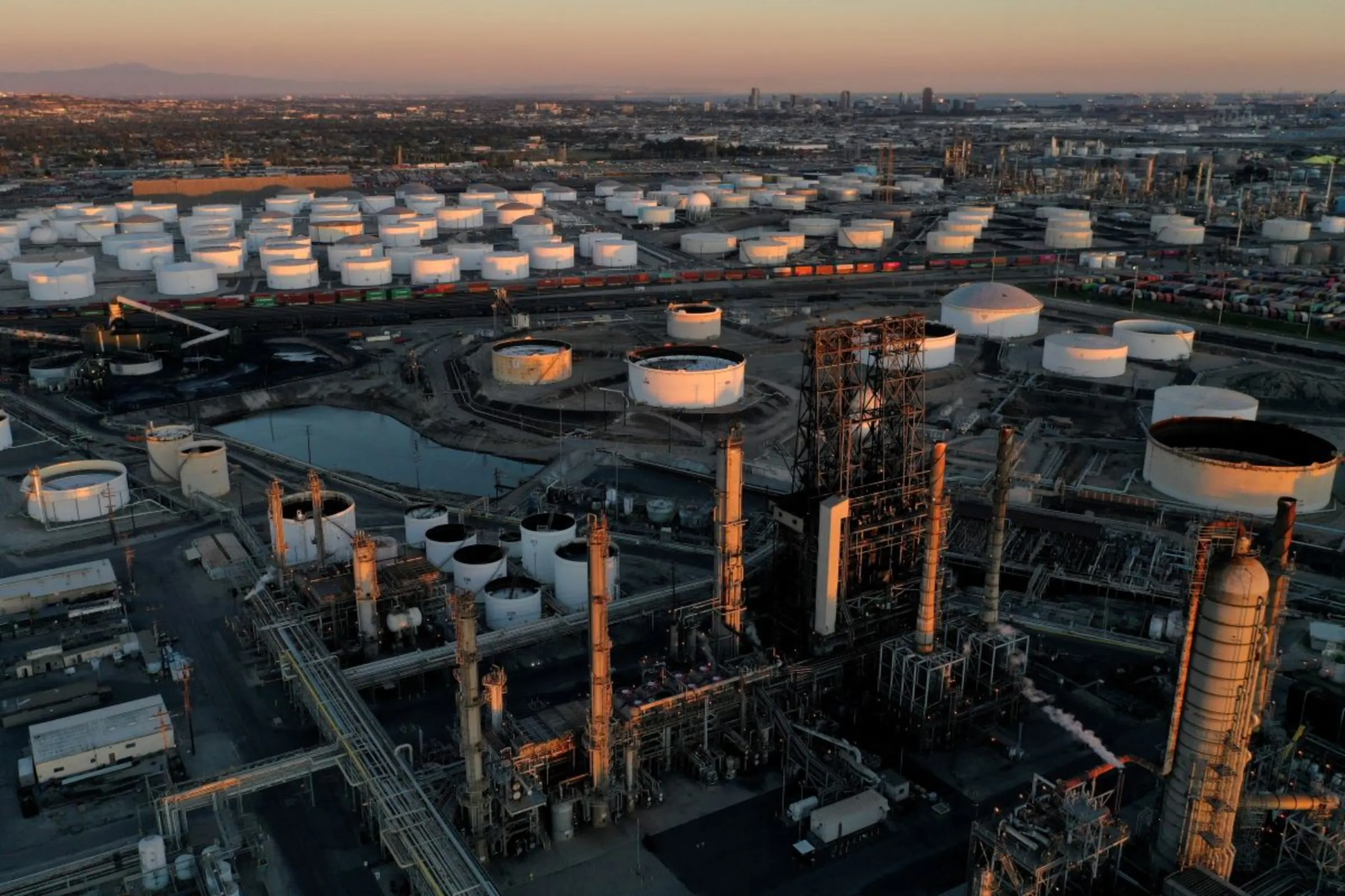 A view of the Phillips 66 Company's Los Angeles Refinery (foreground), which processes domestic & imported crude oil into gasoline, aviation and diesel fuels, and storage tanks for refined petroleum products at the Kinder Morgan Carson Terminal (background), at sunset in Carson, California, U.S., March 11, 2022. Picture taken with a drone. REUTERS/Bing Guan
