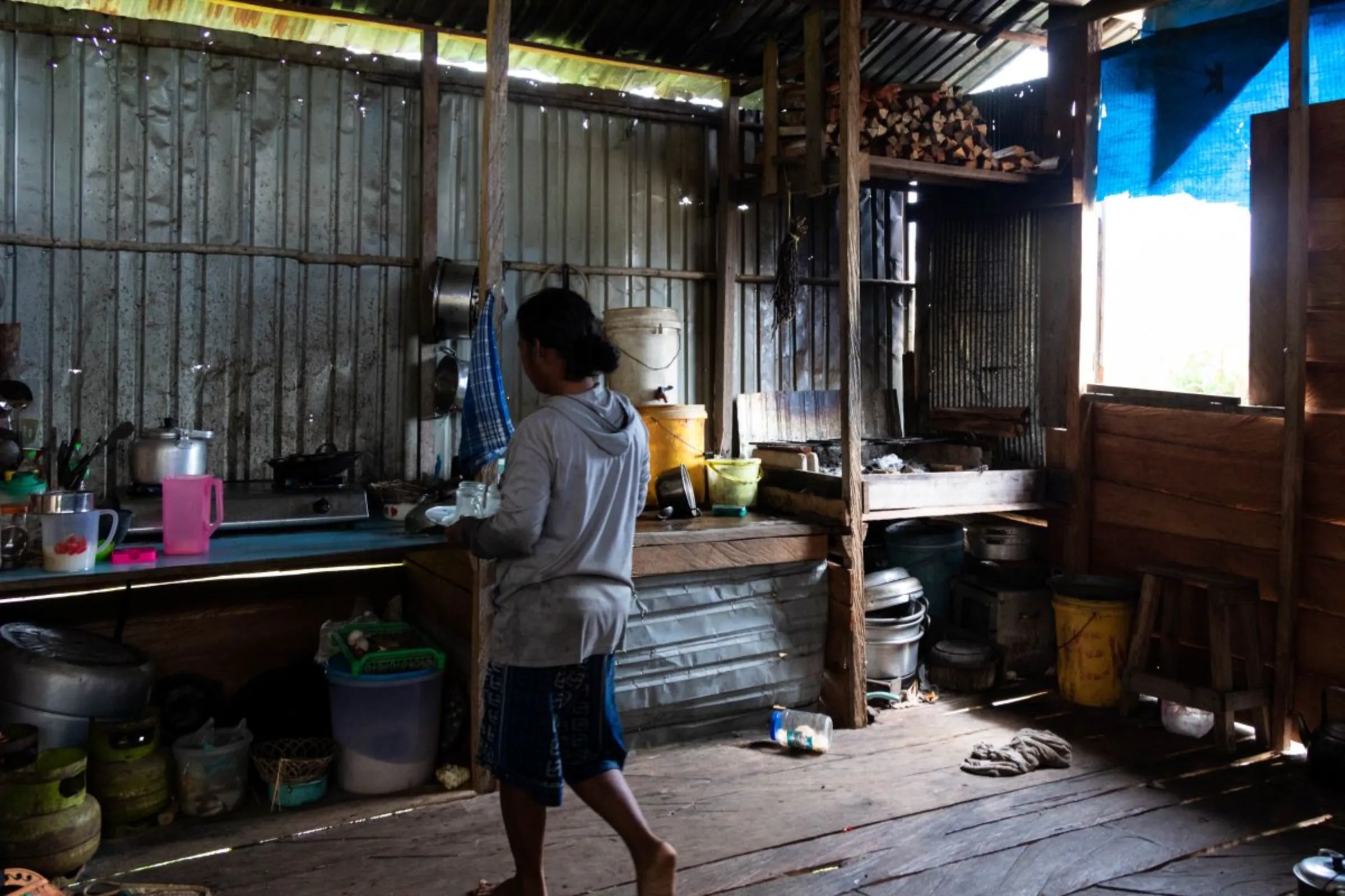 Indah Lestari makes a drink at her home in Central Kalimantan, Indonesia on June 20, 2023. She and her husband are farmers who lost about half of their land  because of the food estate program. Thomson Reuters Foundation/Irene Barlian