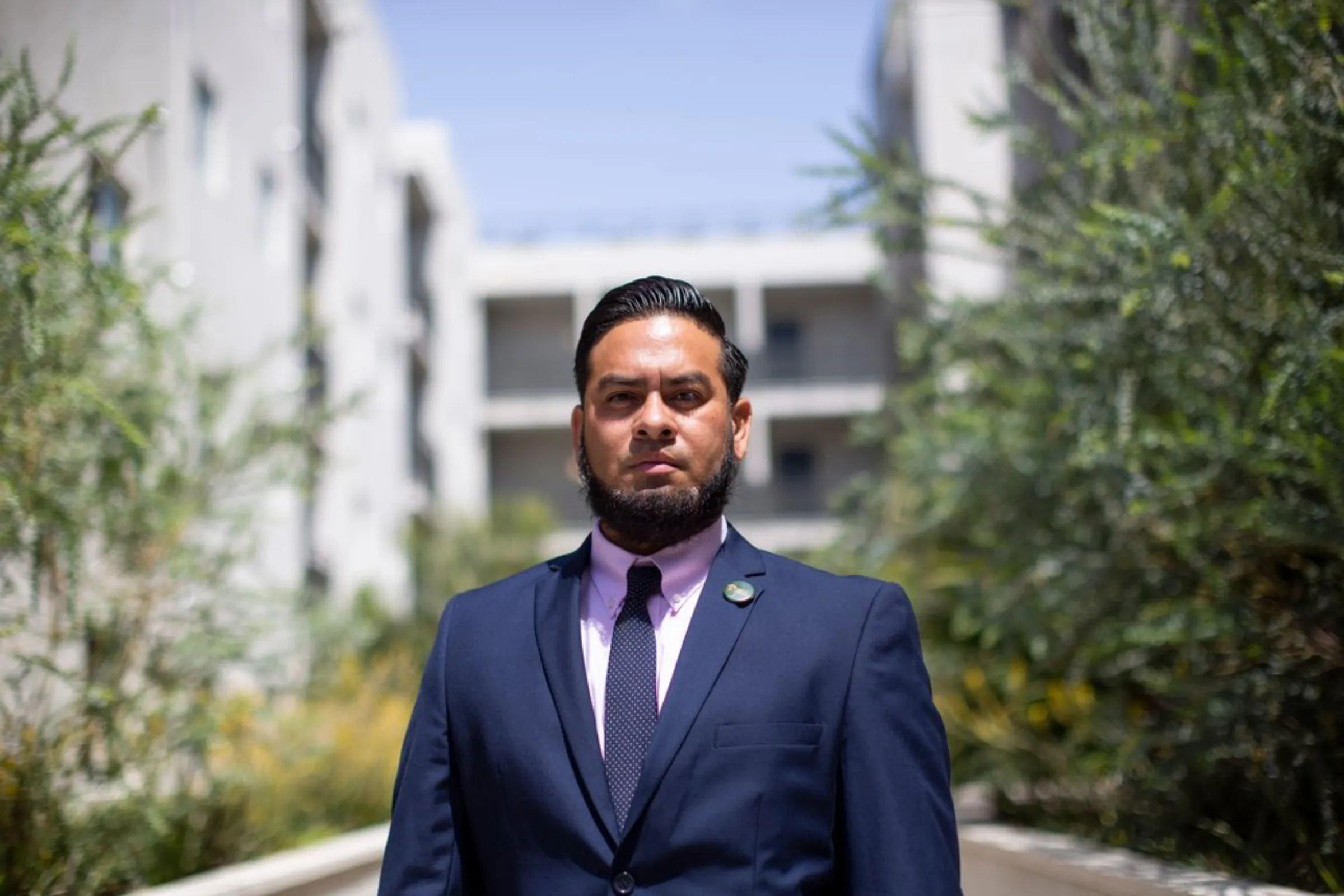 Edgar Campos, the executive direct of T.R.U.S.T. South-L.A., a south Los Angeles community land trust, stands in front of an affordable housing residential development in Los Angeles, May 19, 2021