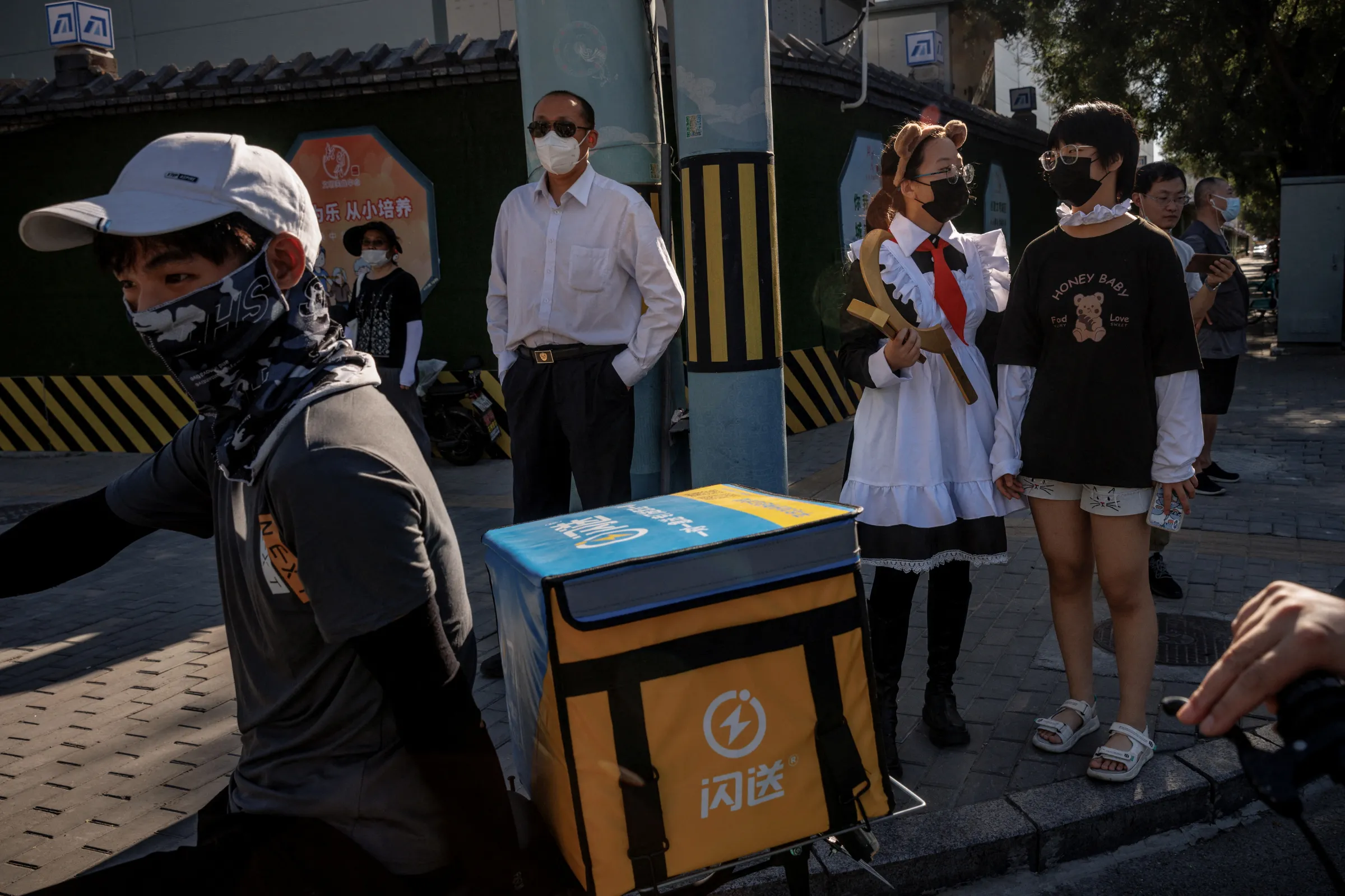 A delivery driver waits with people at a traffic light in Beijing, China, July 14, 2022