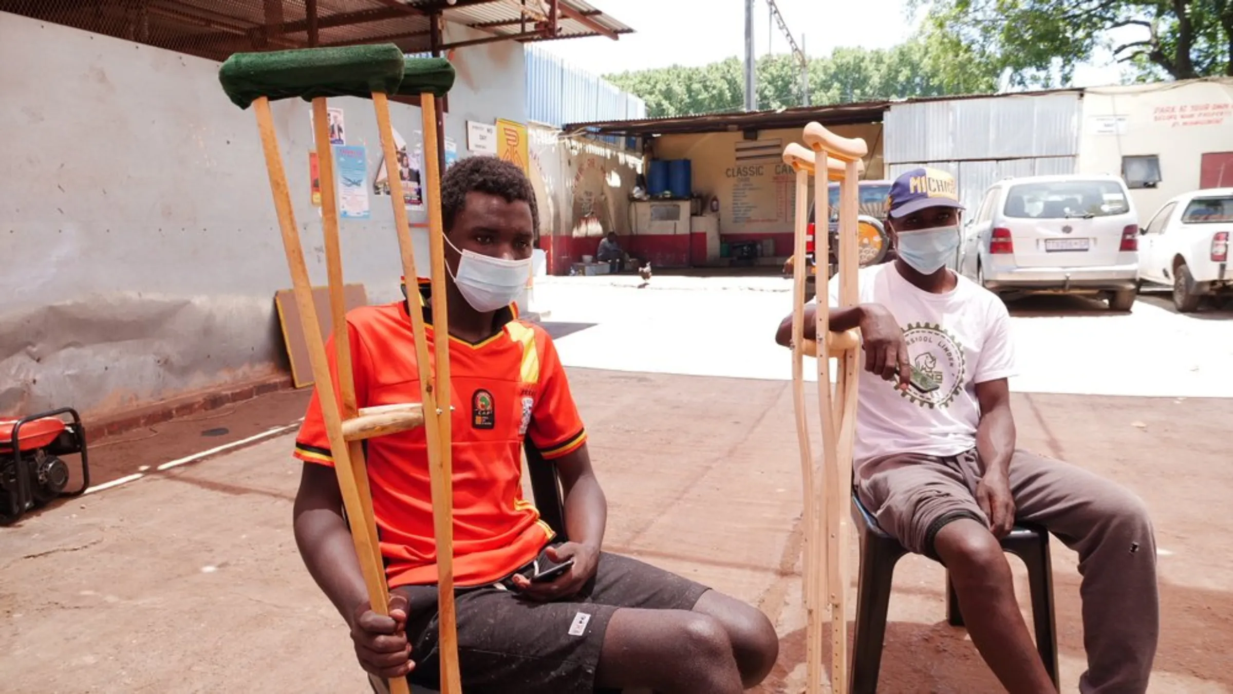 Two former Uber Eats drivers pose for a photo with their crutches after both being in accidents while delivering for the app in Johannesburg, South Africa. January 22, 2021. Thomson Reuters Foundation/Kim Harrisberg