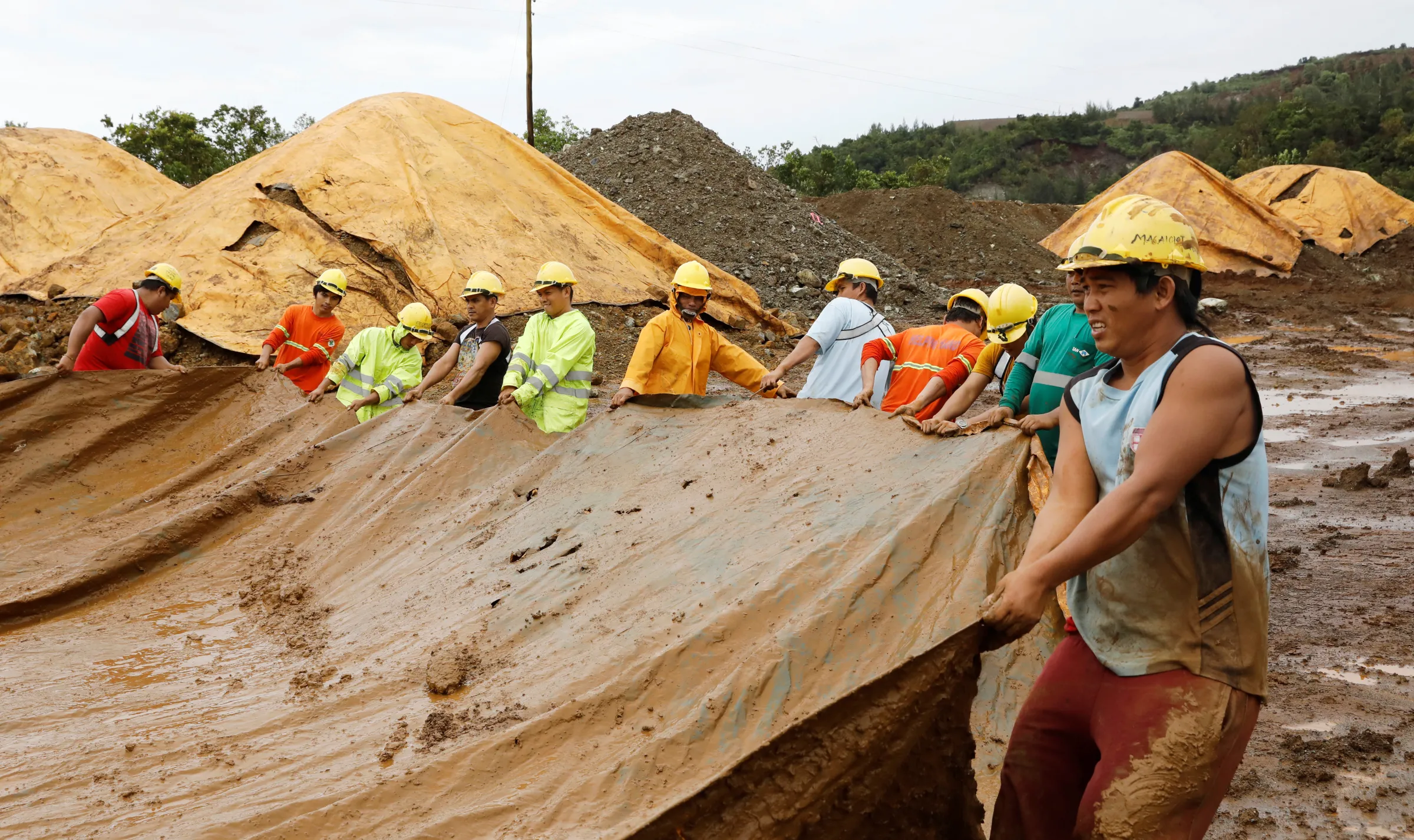 Workers of SR Metals cover a stockpile of nickel-ore minerals with a tarp to avoid moisture in Tubay, Agusan del Sur, in southern Philippines February 16, 2017. REUTERS/Erik De Castro