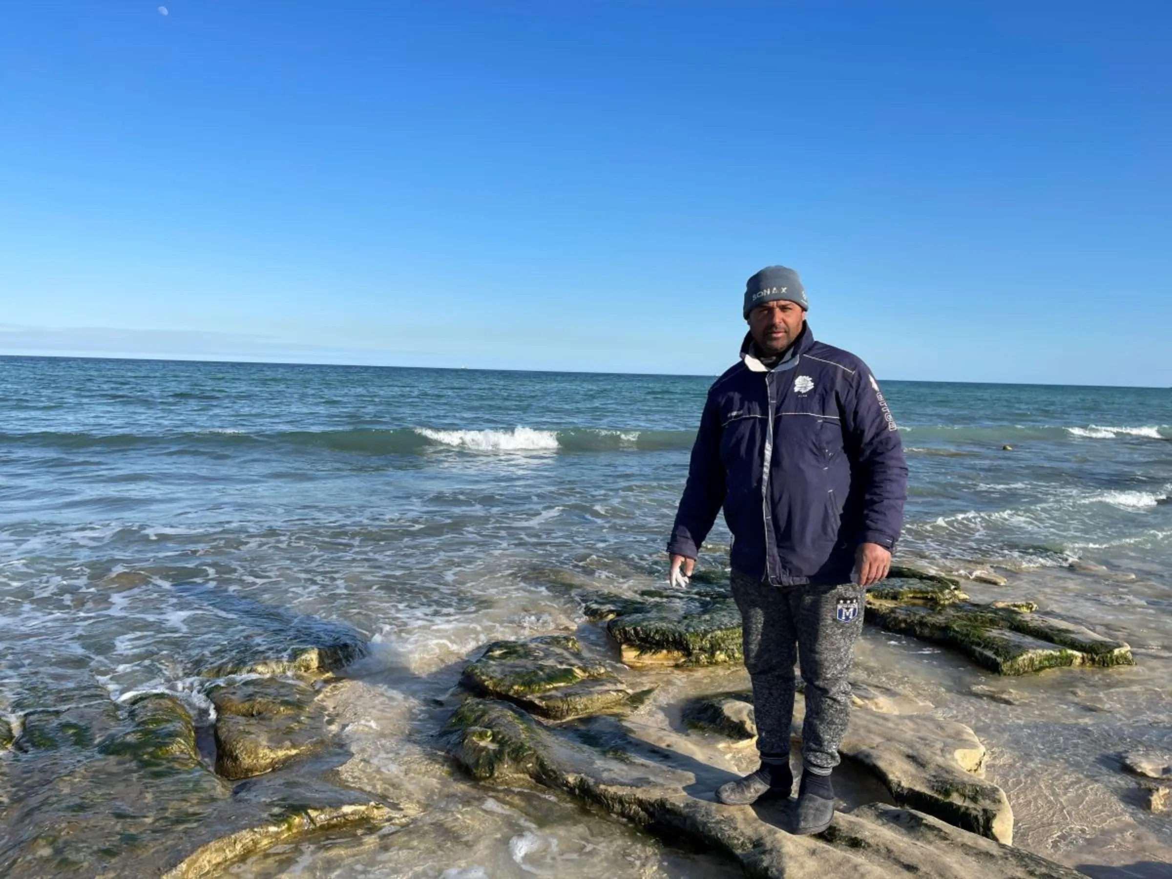 Mohamed Ali, a 39-year-old fisherman, stands on the shoret in Ghannounch, Gabes, southern Tunisia on February 1, 2022. Thomson Reuters Foundation/Menna A. Farouk