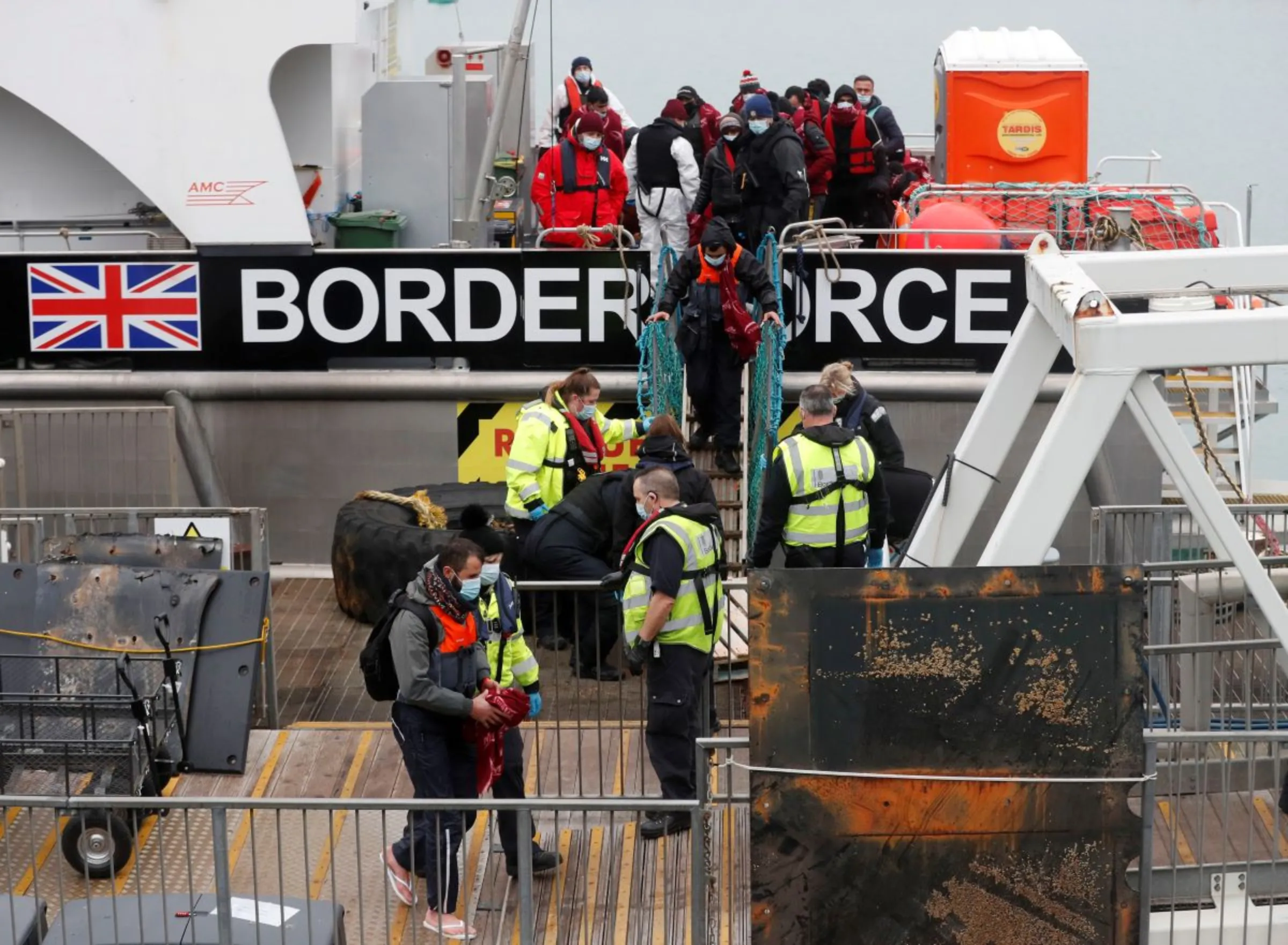 Migrants who arrived onboard a Border Force rescue boat are escorted by Border Force staff, after having crossed the channel, at Dover harbour in Dover, Britain, December 15, 2021. REUTERS/Matthew Childs