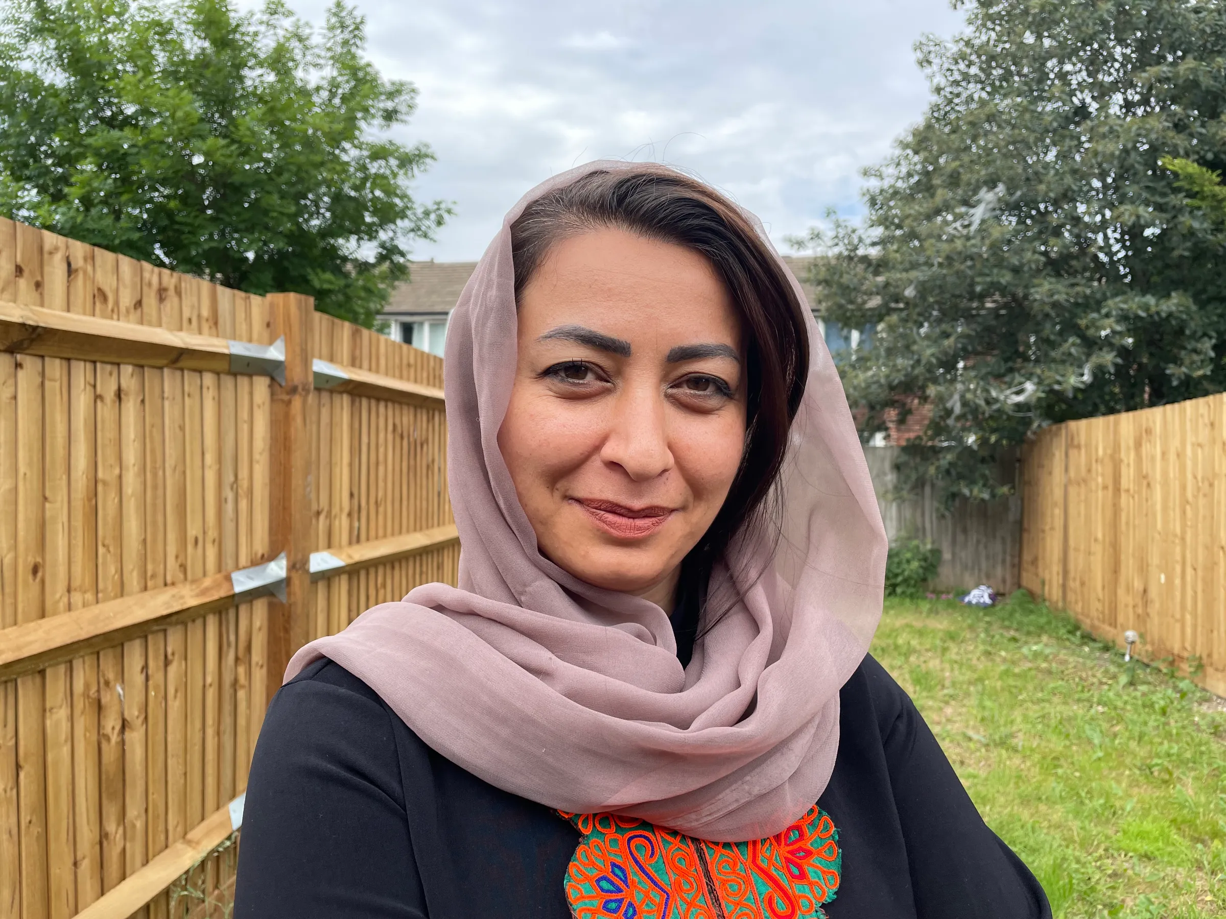 A woman in a headscarf smiles at the camera