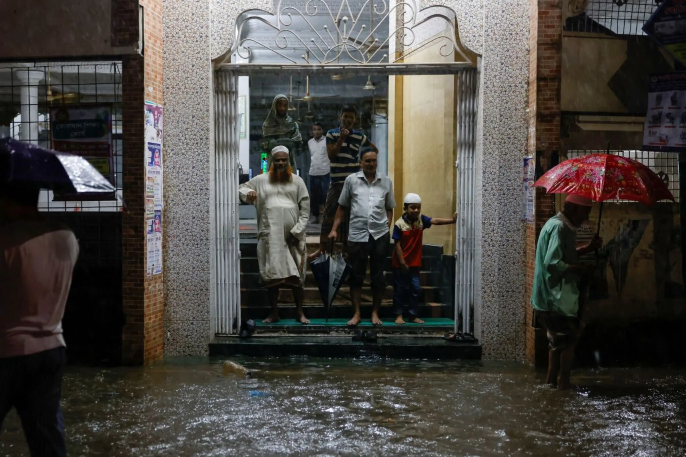 People wait by a mosque as streets are flooded before the Cyclone Sitrang hits, Dhaka, Bangladesh, October 24, 2022. REUTERS/Mohammad Ponir Hossain