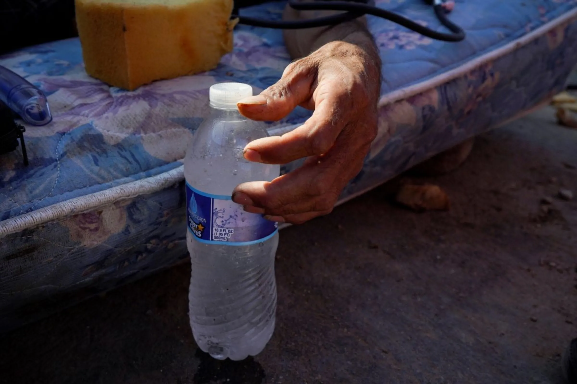 A man showing symptoms of heat exhaustion touches a bottle of water provided by paramedics during a heatwave in Mexicali, Mexico, July 20, 2023. REUTERS/Victor Medina