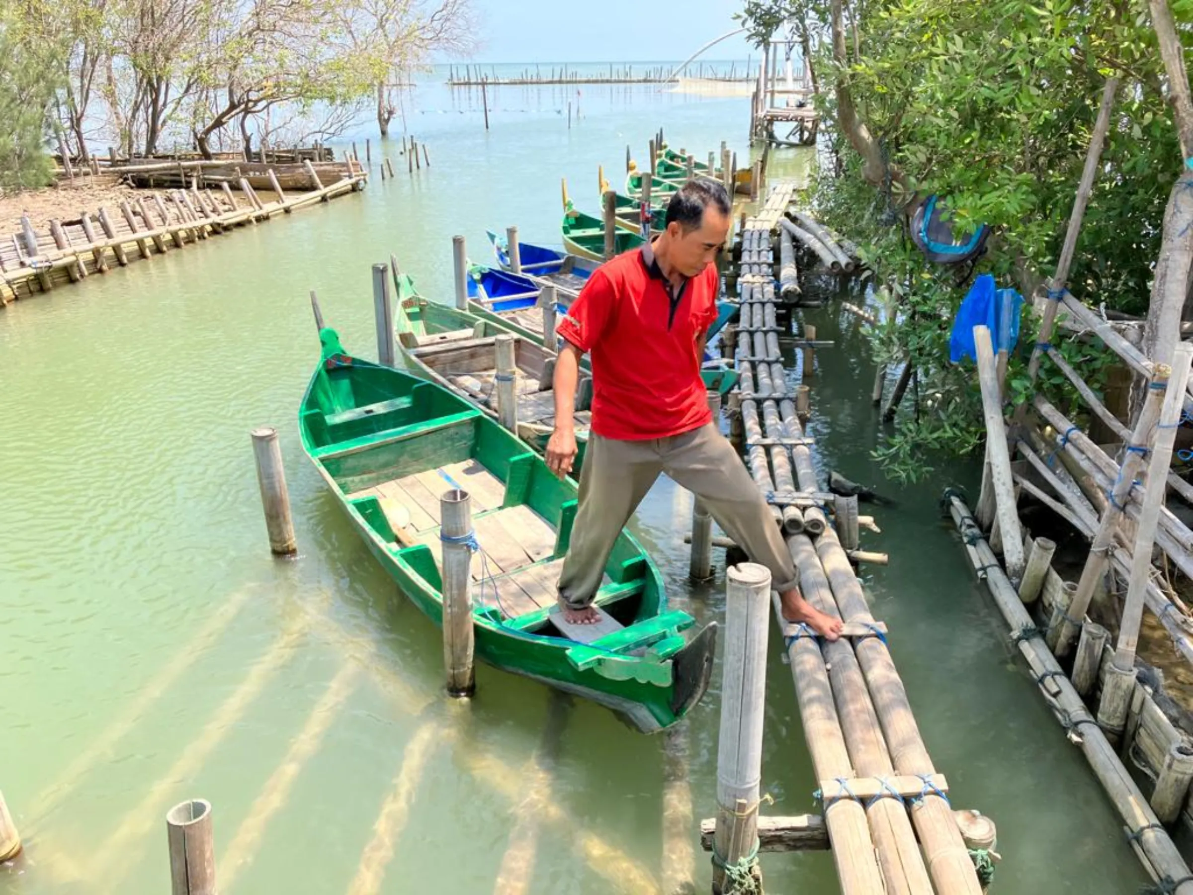 Fisherman Suratno steps off one of his boats outside his home in Timbulsloko village in Demak, Indonesia on August 30, 2022. Thomson Reuters Foundation/Michael Taylor