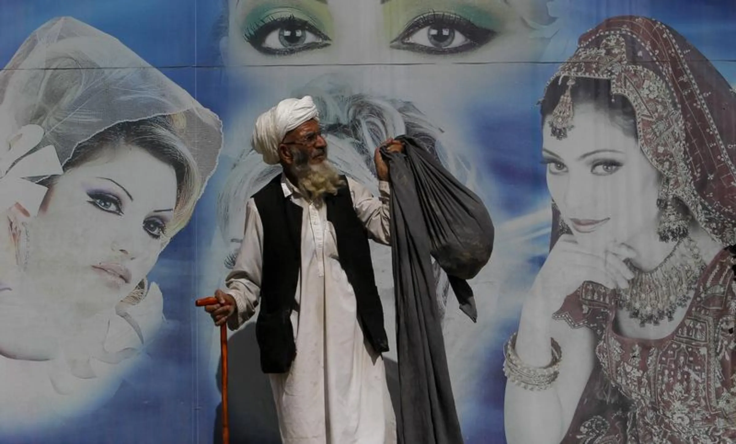 An Afghan man stands in front of a beauty saloon shop in Kabul