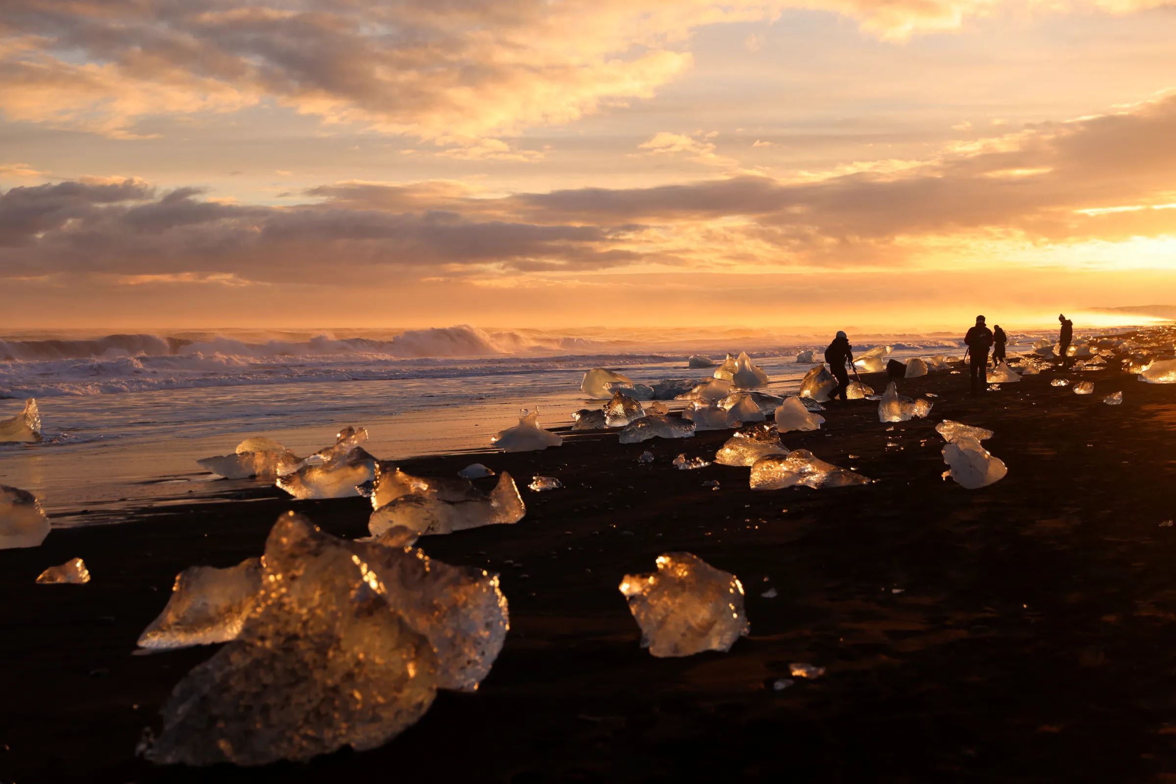 Tourists look at the blocks of ice that have broken off Jokulsarlon glacier lagoon at Diamond beach during the winter in the southern coast of Iceland February 17, 2022. REUTERS/Nacho Doce