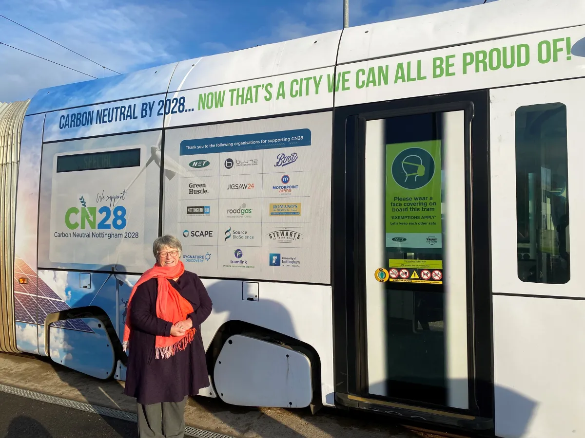 Councillor Sally Longford poses beside a Nottingham Express Transit (NET) tram covered in Carbon Neutral Nottingham 2028 promotional livery in Nottingham, United Kingdom in an undated photograph.
