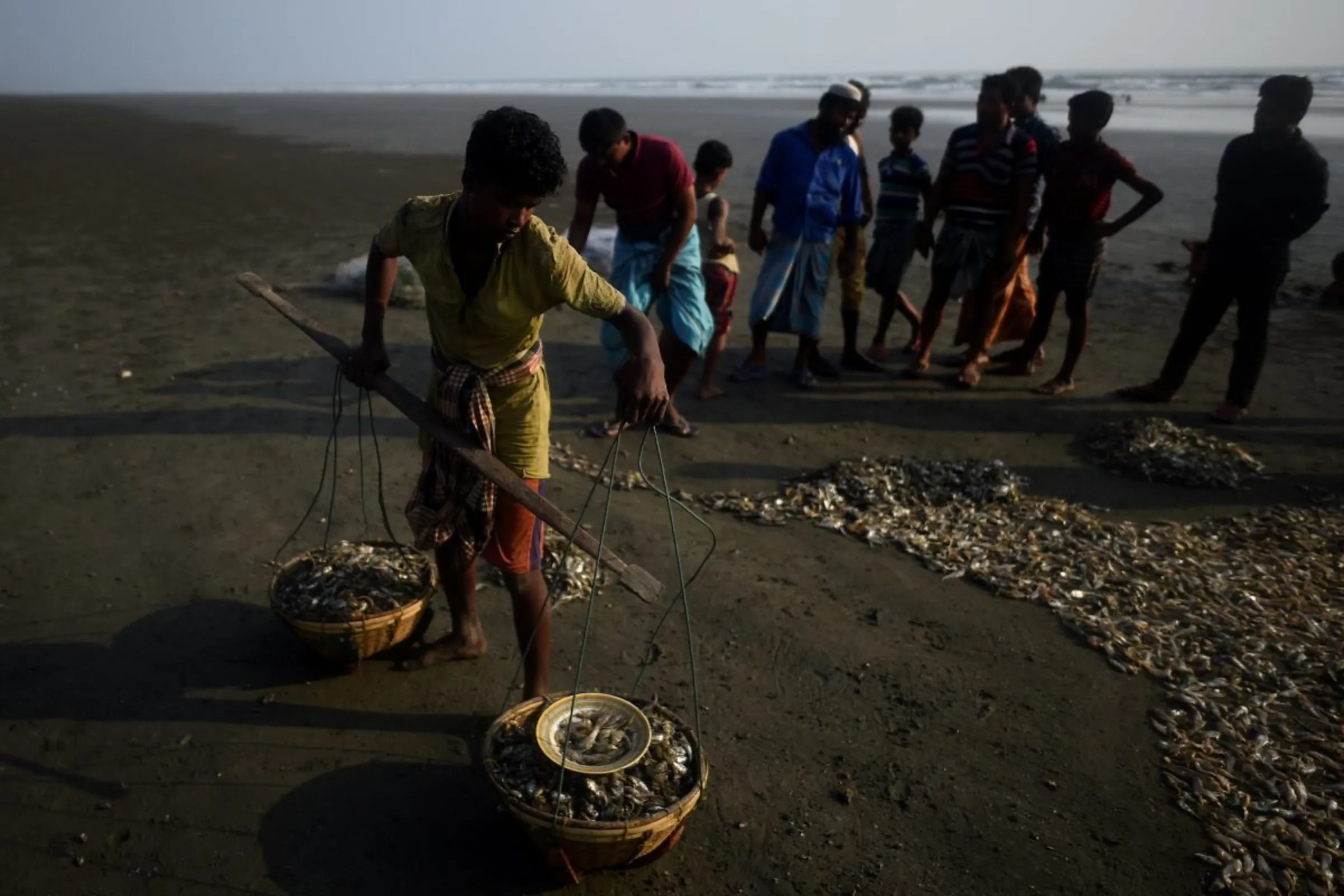 A Rohingya refugee buys fish on Shamlapur beach in Cox's Bazaar, Bangladesh, March 21, 2018. REUTERS/Clodagh Kilcoyne