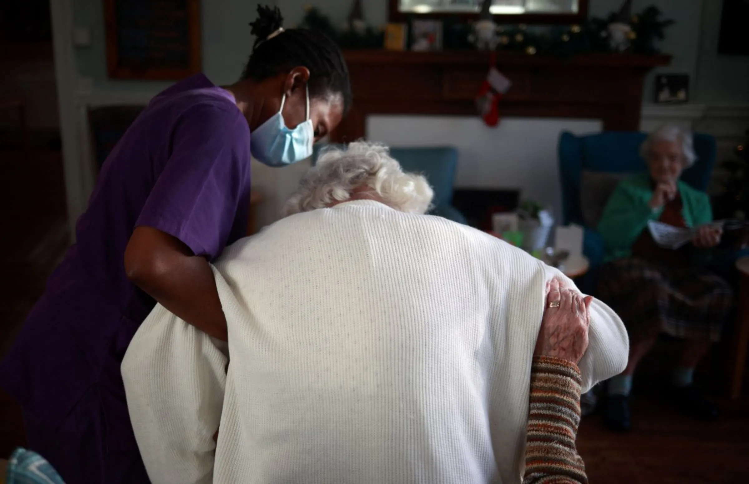 A care worker assists a resident at a care home in south London, Britain, December 25, 2020. REUTERS/Hannah McKay