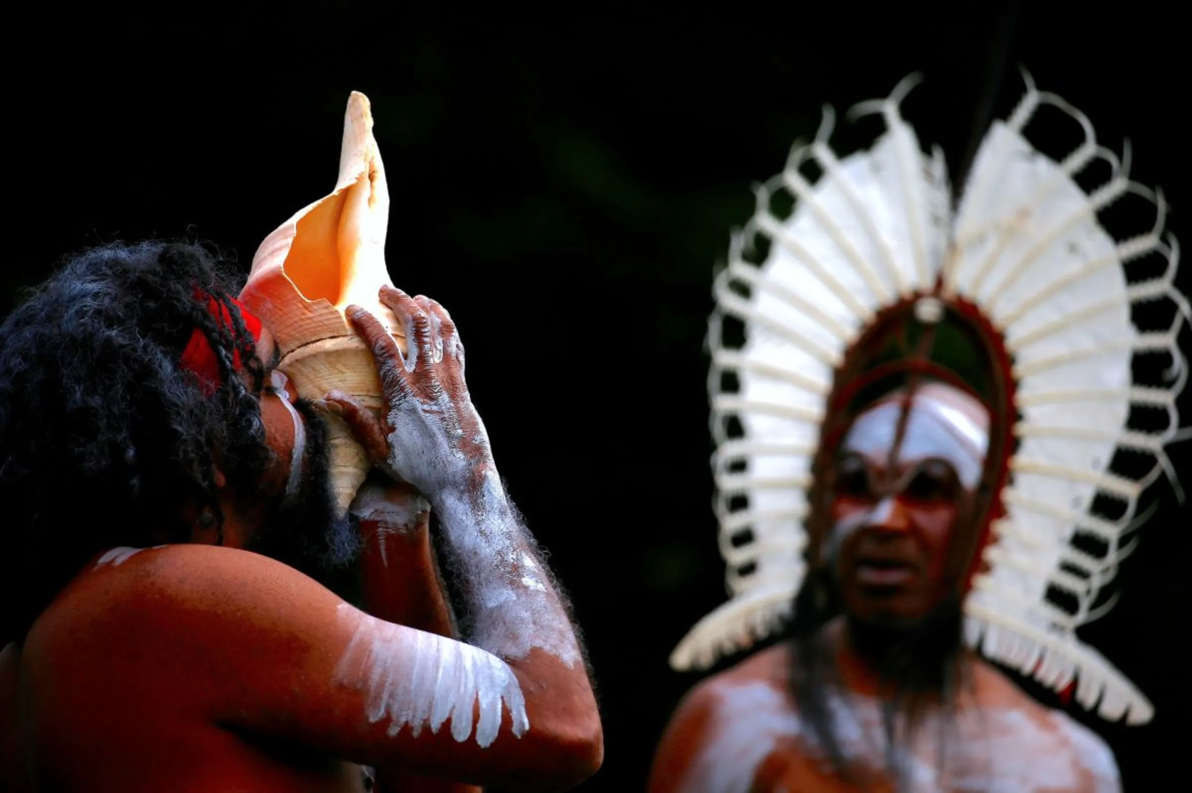 An Australian Aboriginal man blows into a shell as an indigenous man from the Torres Strait Islands wearing traditional dress performs during a welcoming ceremony at Government House in Sydney, Australia, June 28, 2017