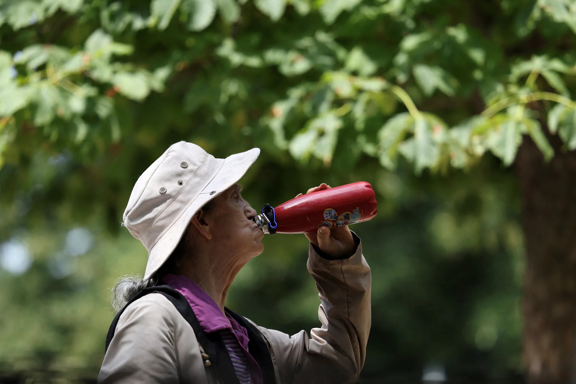 A woman drinks water at Retiro park during a heatwave, in Madrid, Spain, July 1, 2025. REUTERS/Juan Medina