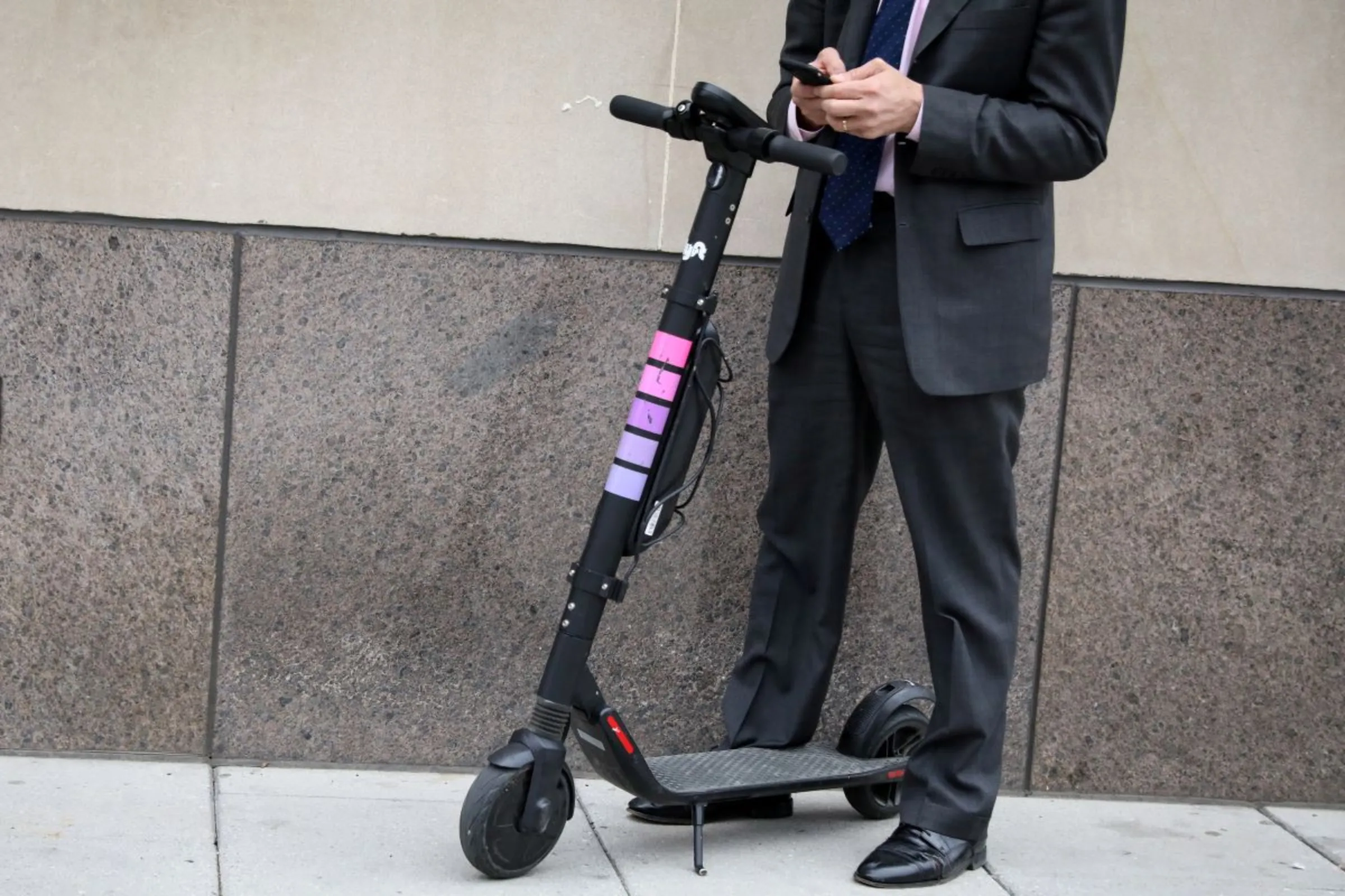 A man uses his phone to activate a Lyft Scooter in Washington, U.S., March 29, 2019