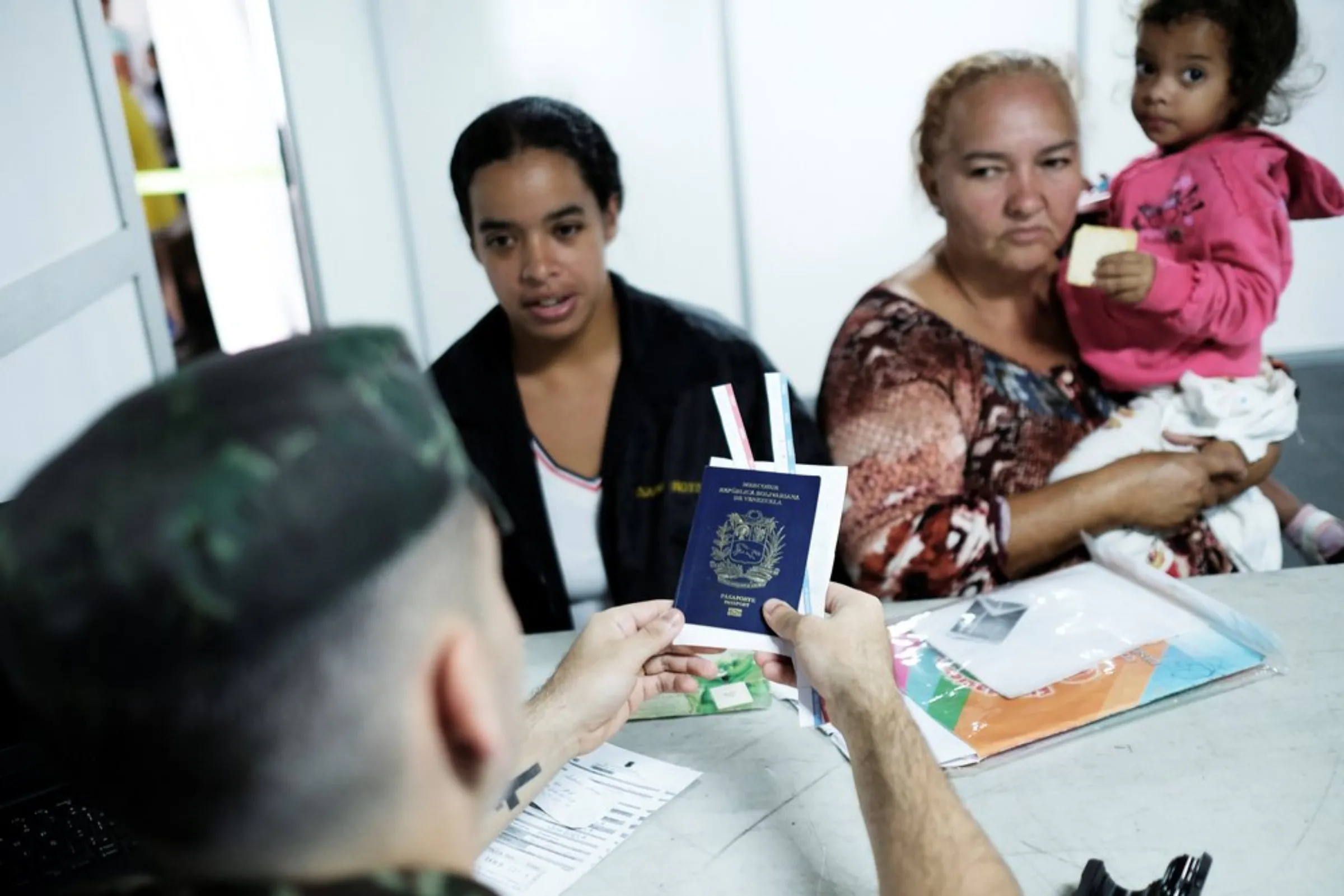 A military officer delivers a Venezuelan family's passports along with a medical inspection before they apply for refugee status, through the Federal Police and the United Nations High Commissioner for Refugees (UNHCR) at the Pacaraima border control, Roraima state, Brazil August 9, 2018