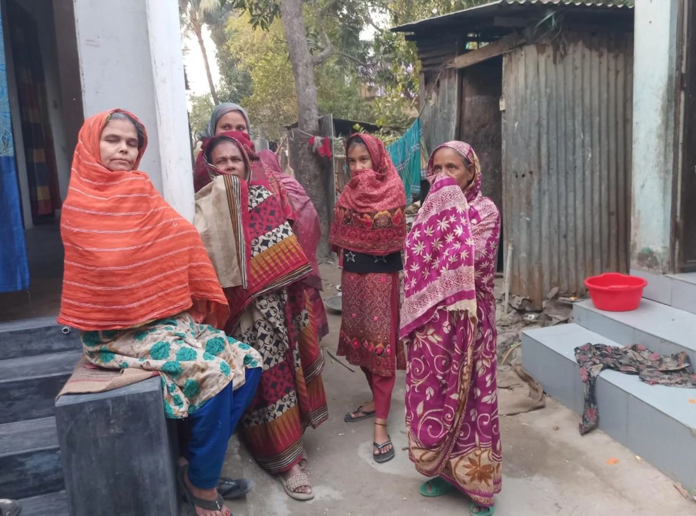 Local women, gathered for an evening chatter in their yard, say they used to pick water spinach and other sources of nutrition in the area that now falls under the zone, Narayanganj, Bangladesh, January 11, 2023, Thomson Reuters Foundation/ Md. Tahmid Zami