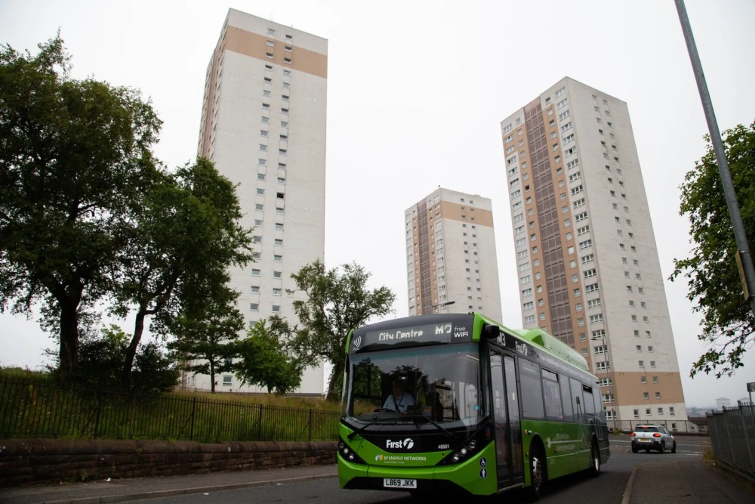 An electric bus drives past high-rise flats in the northern Springburn district in Glasgow, United Kingdom, July 22, 2021