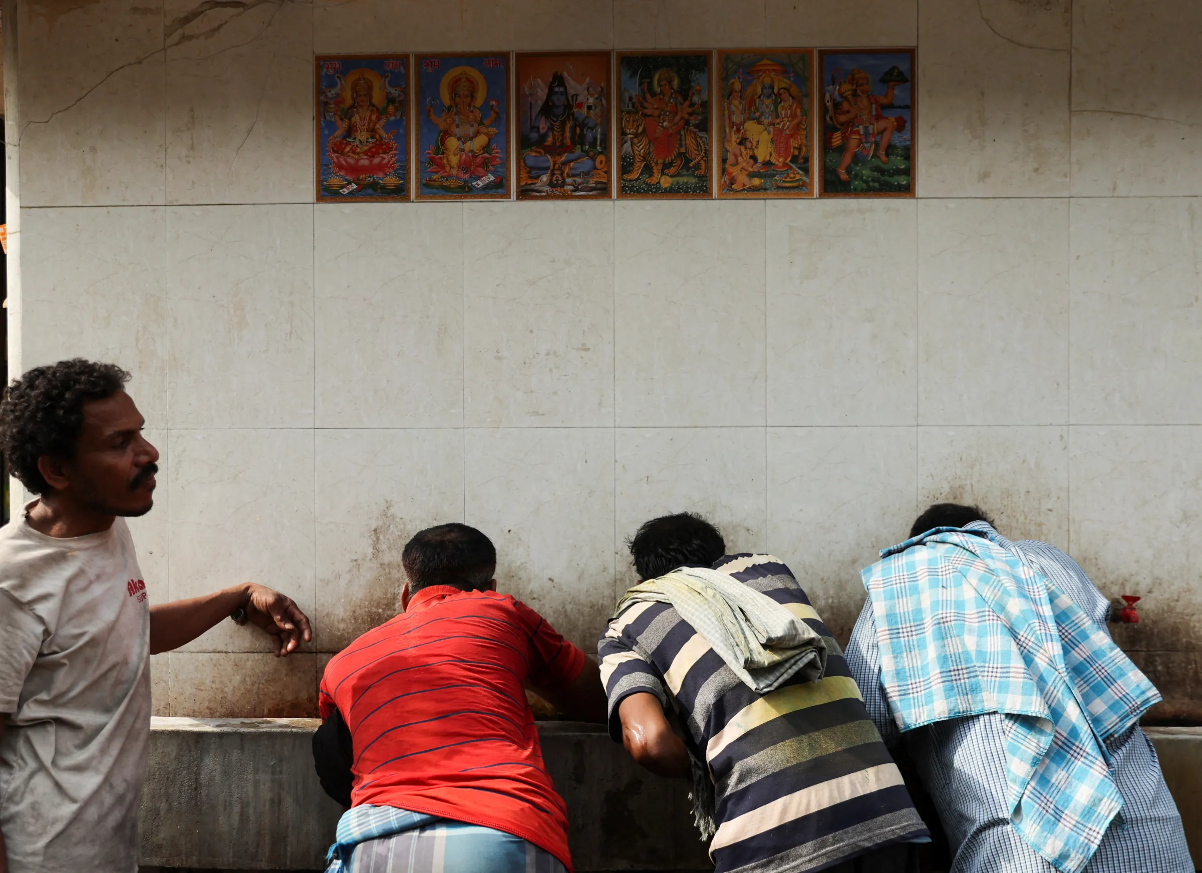 Labourers drink water from a public drinking water tap on a hot summer day in the old quarters of Delhi, India, May 4, 2022. REUTERS/Anushree Fadnavis