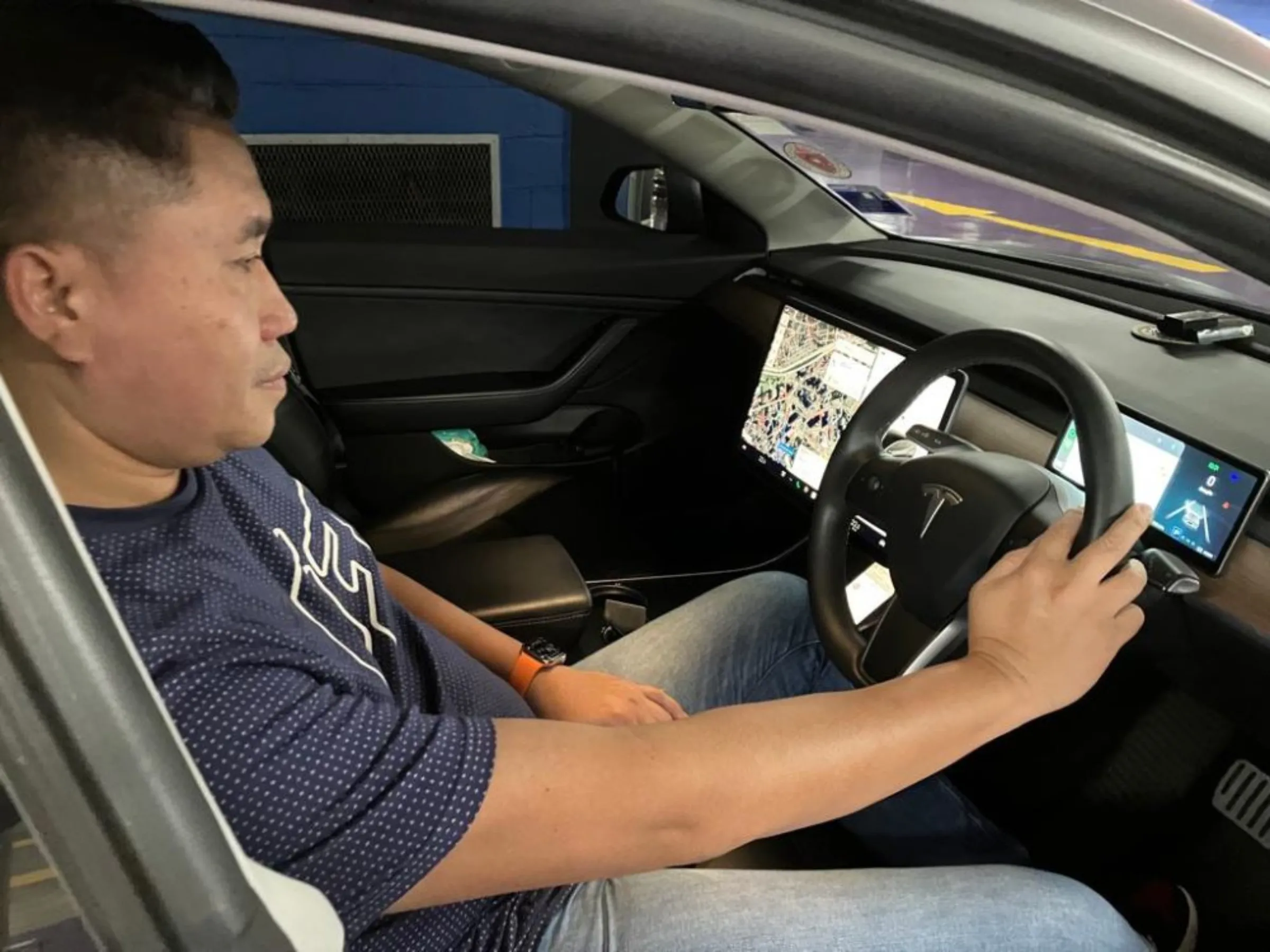 Malaysian Farhan Abdul Rahim sits inside his Tesla electric car in the car park under the iconic Petronas Twin Towers in Kuala Lumpur, Malaysia on Feb 15, 2023