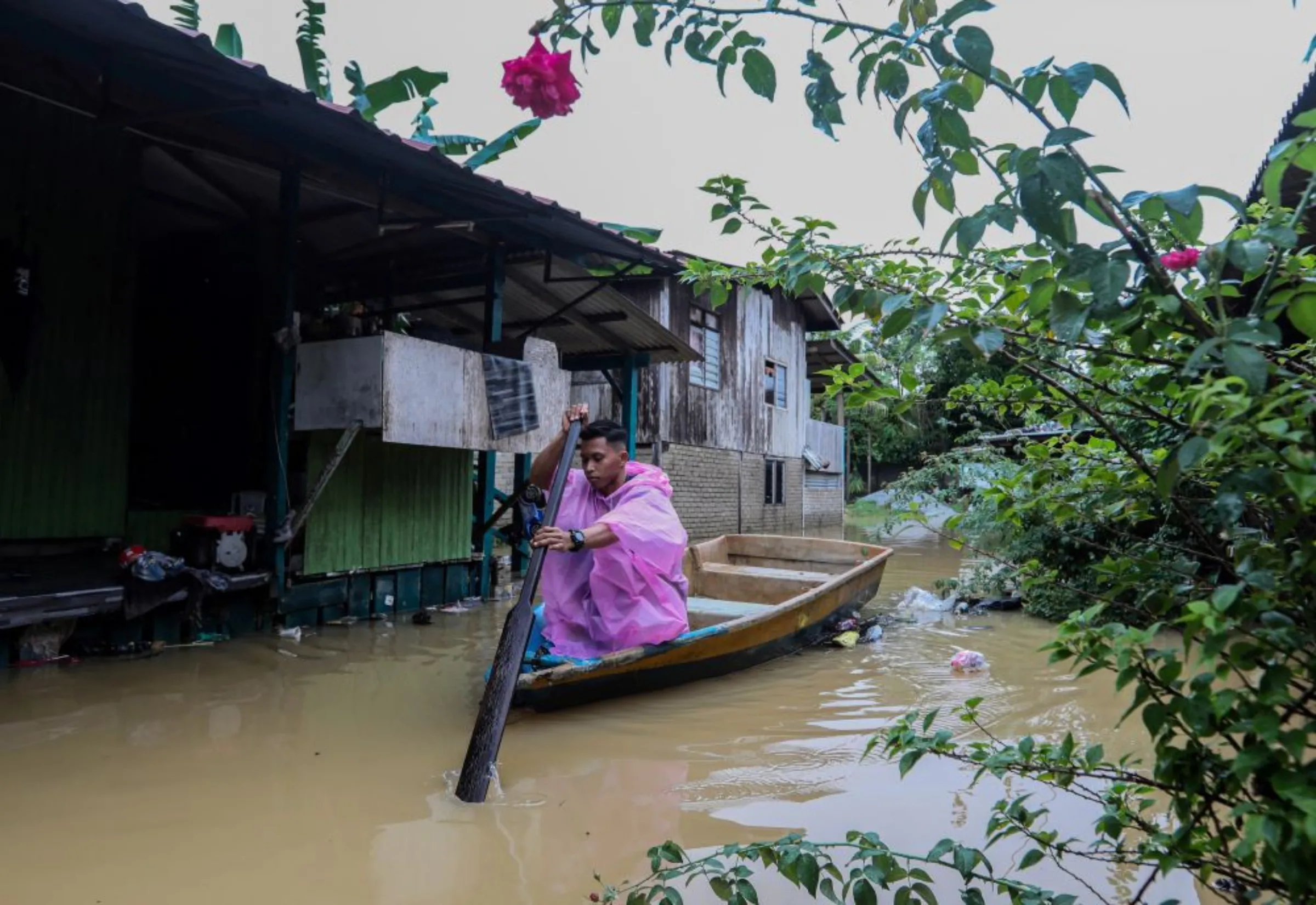 A man paddles a boat passing by a partially submerged house by flood water in Kuala Terengganu, Terengganu, Malaysia December 21, 2022. More than 70000 were forced into relief centres, with numbers rising in Kelantan, Terengganu and Pahang, according to local media