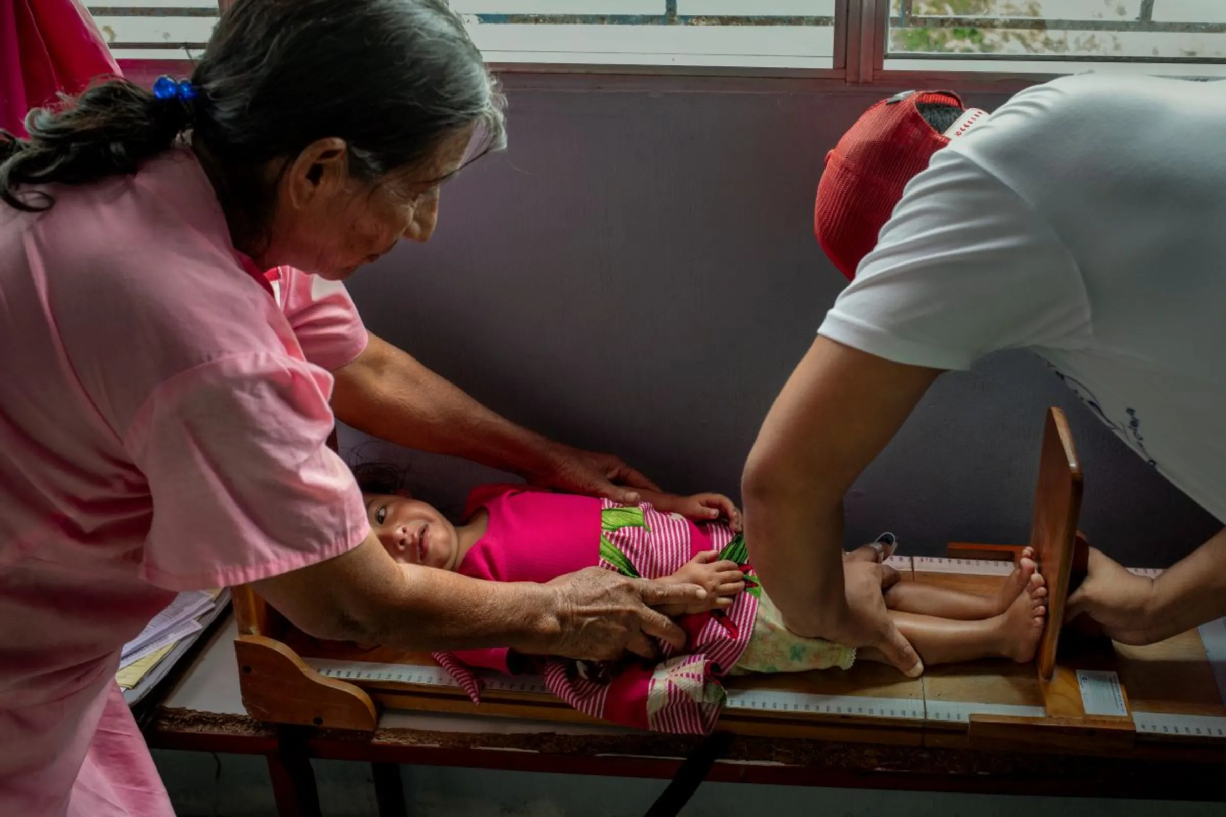 A government nurse checks the height of a malnourished child with her grandmother during a medical check-up in a remote rural clinic in the Camotán municipality in the province of Chiquimula, Guatemala, September 8, 2023. Thomson Reuters Foundation / Fabio Cuttica