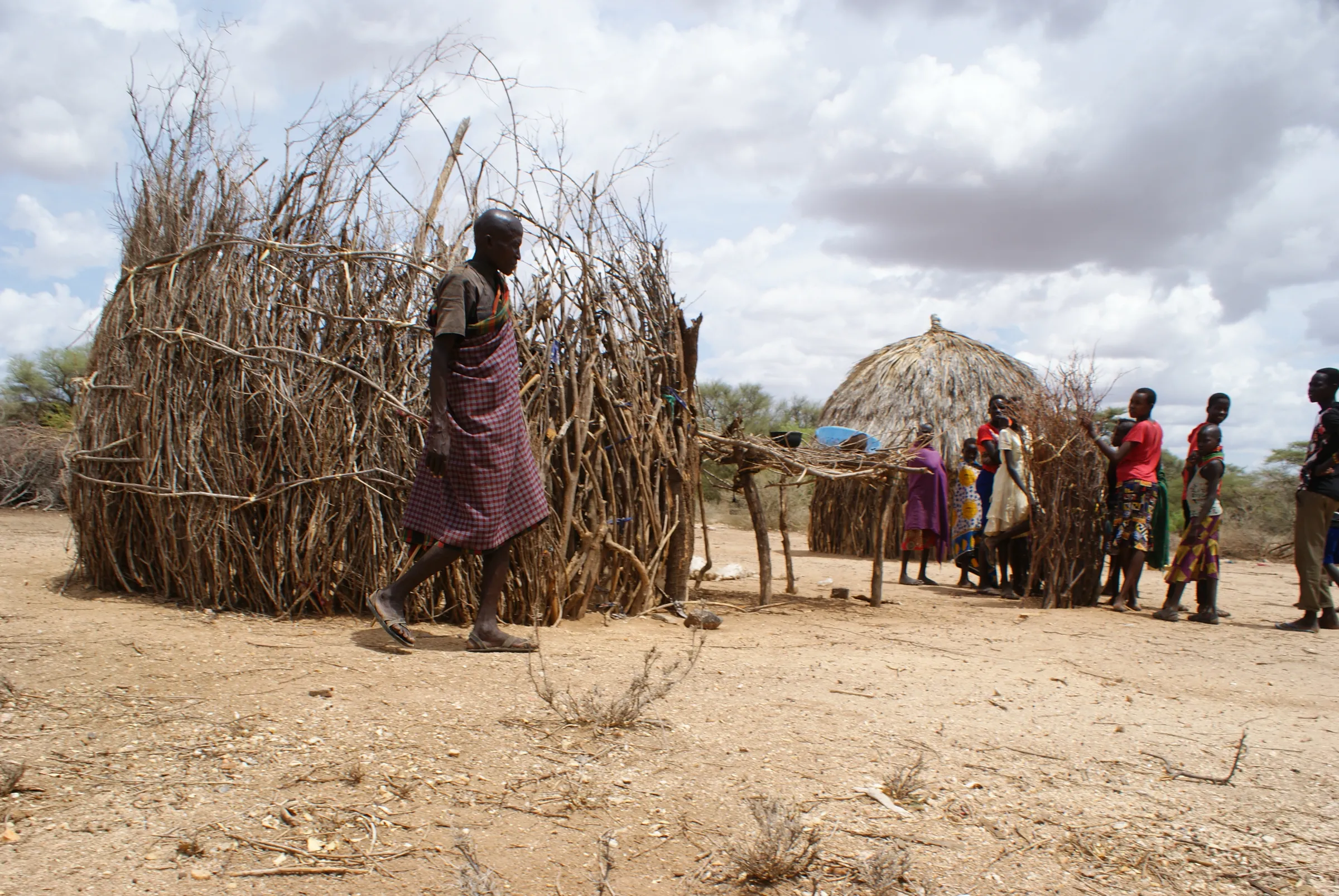 An older man walks through a compound of rural homes in northern Kenya