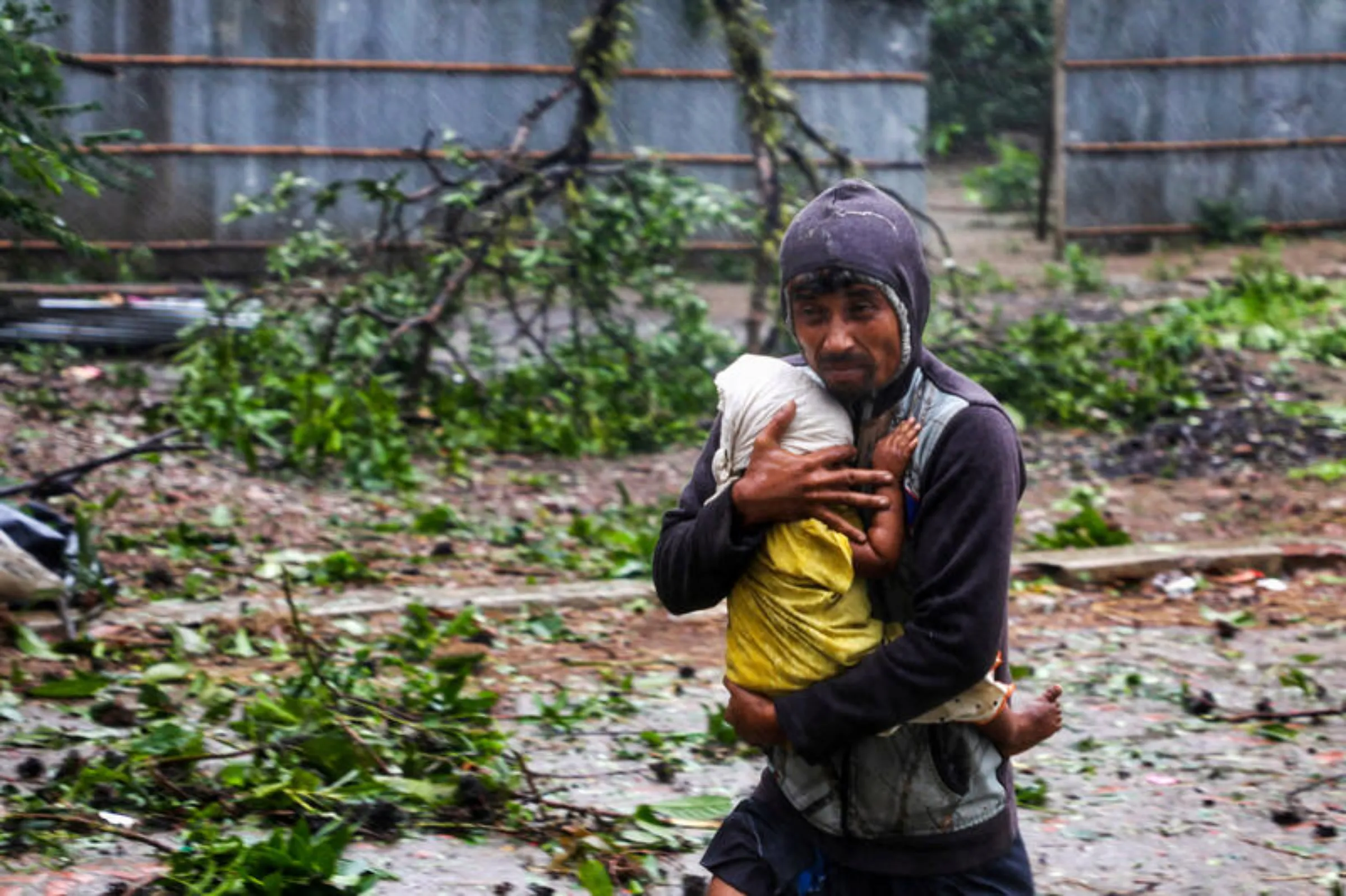 A man holds a child as he moves to the nearest cyclone shelter at Shah Porir Dwip during the landfall of Cyclone Mocha in Teknaf, Bangladesh, May 14, 2023. REUTERS/Jibon Ahmed
