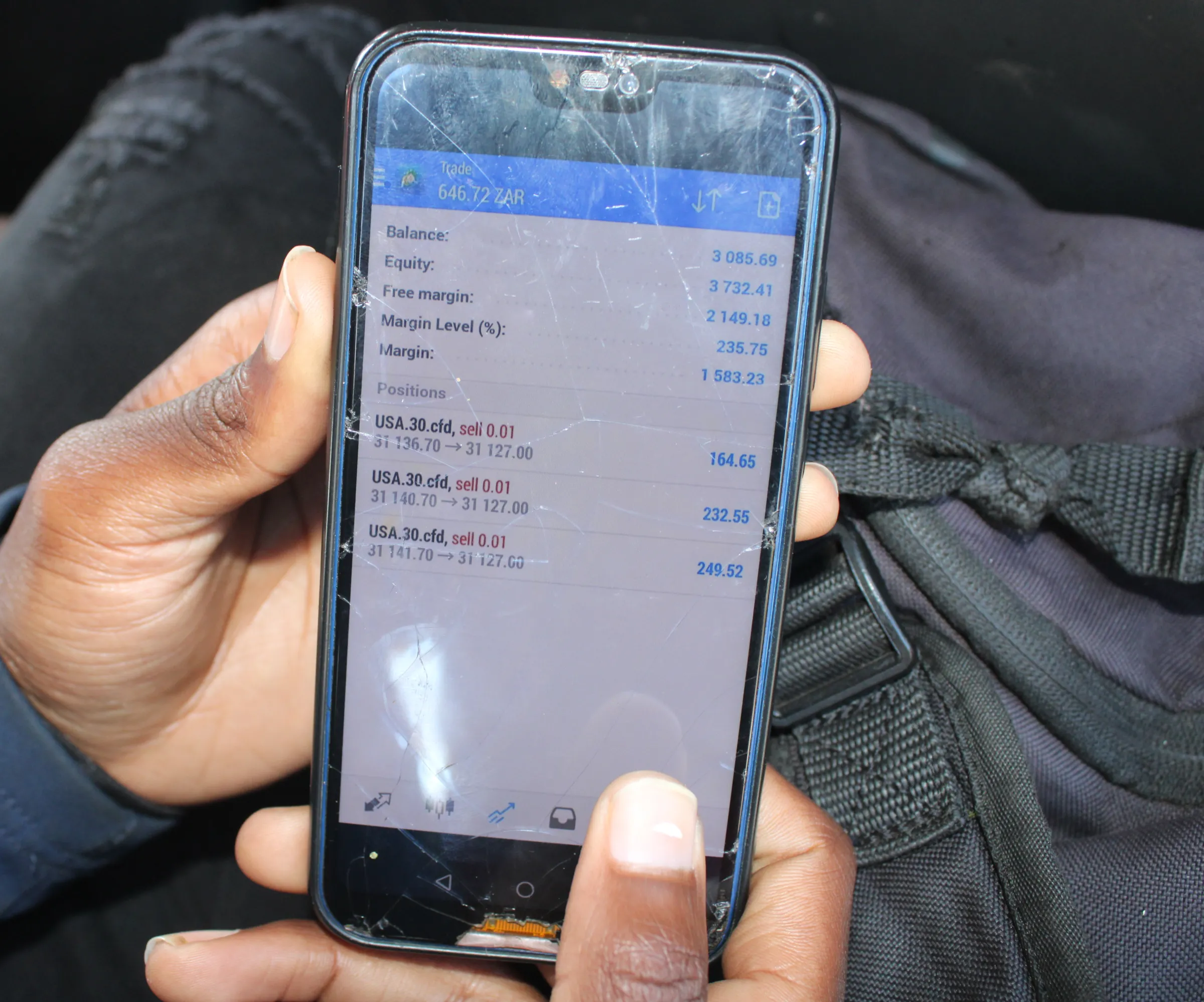 A young man shows his cryptocurrency trades on his mobile phone in KwaThema Township, South Africa.  August 21, 2022. Thomson Reuters Foundation/Kimberly Mutandiro