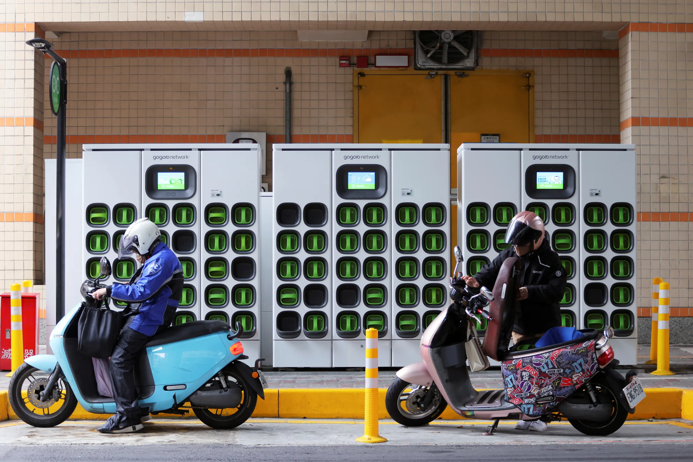 Riders stop in front of a battery-swapping station by Taiwanese electric scooter maker Gogoro Inc in Taipei, Taiwan April 19, 2022