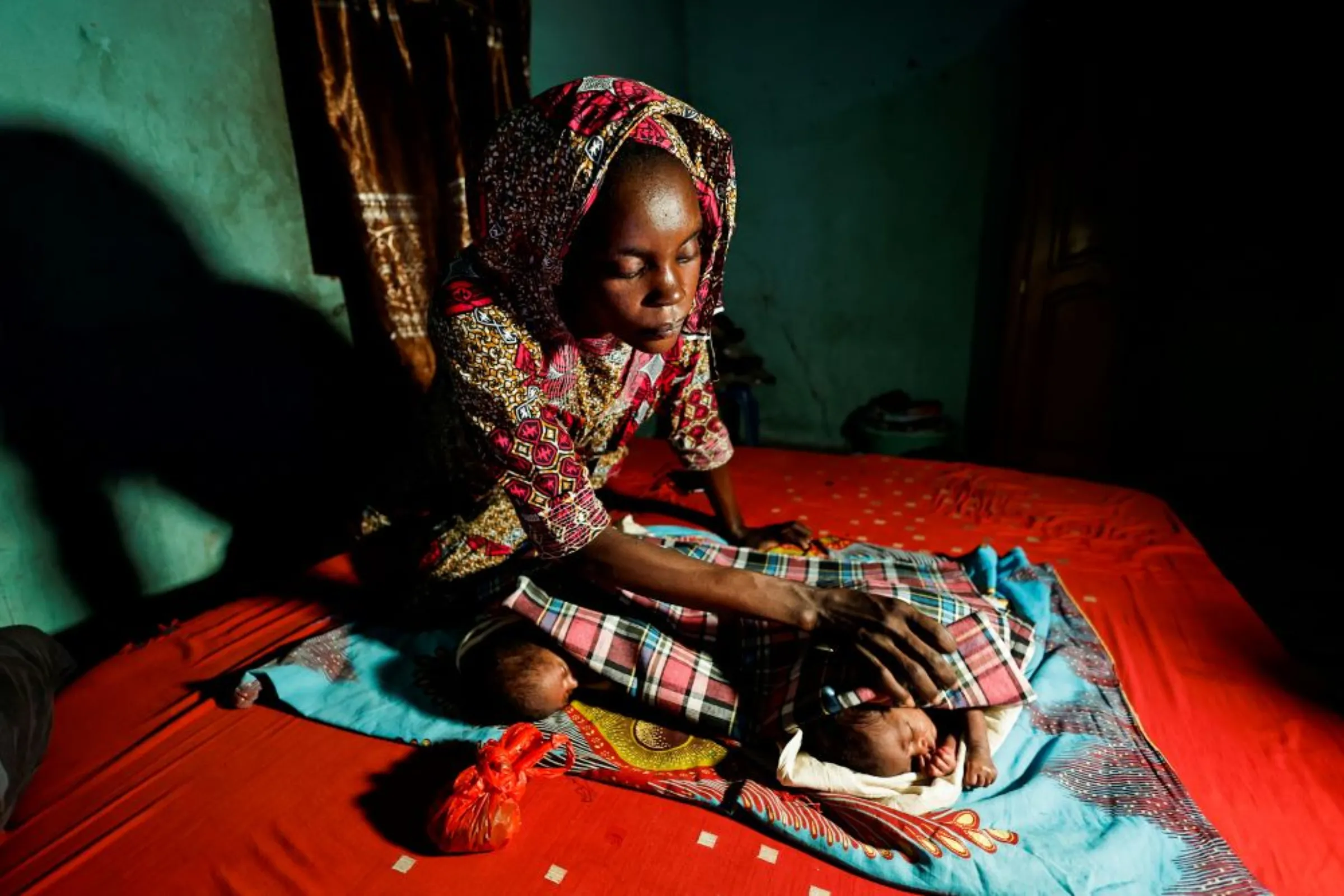 A mother checks on her two babies as they lie on her bed at her house in Keur Assane Mbaye village, Thies region, Senegal May 26, 2022