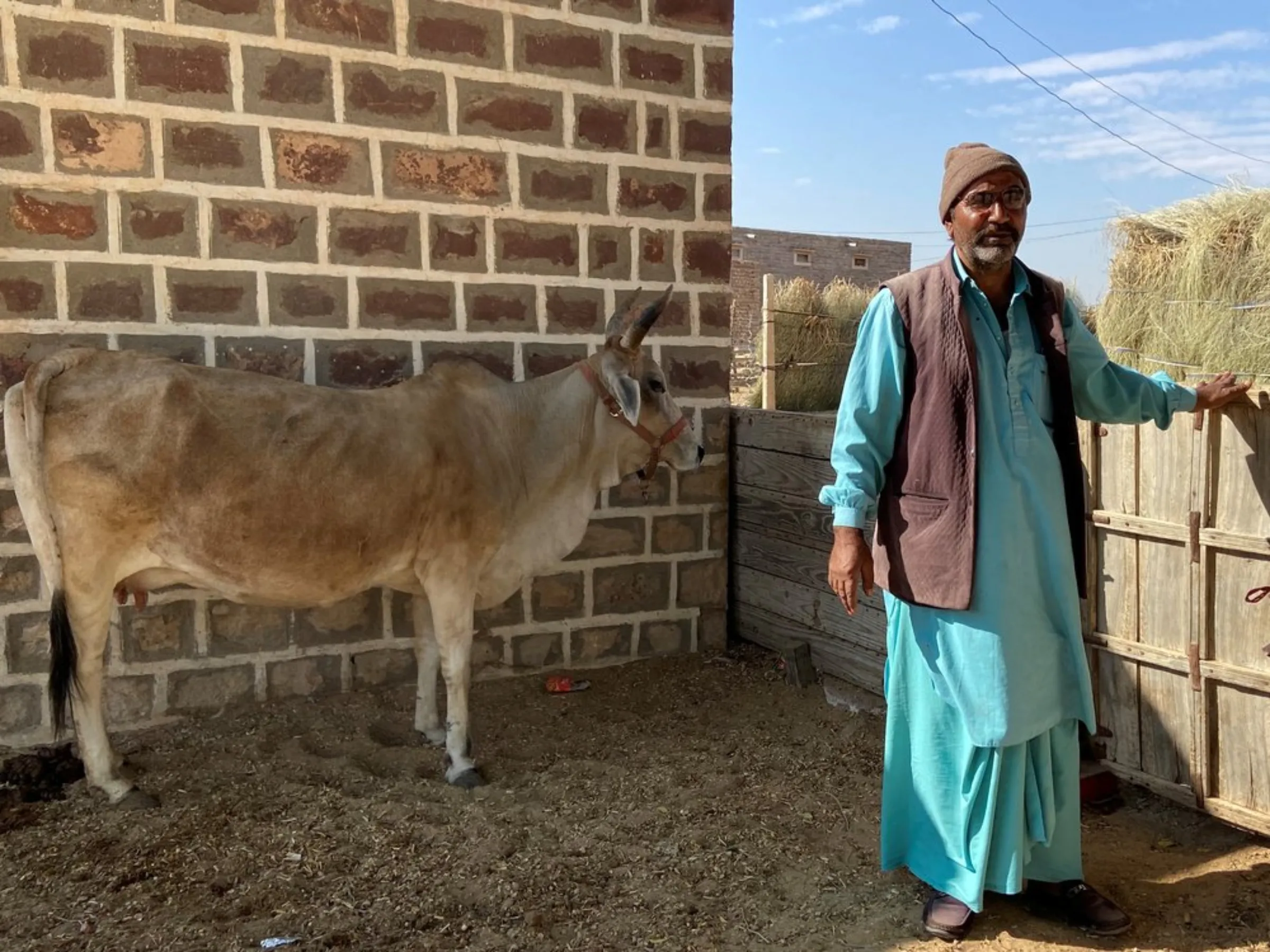 Mohammad Sujawal Mehr poses for a picture with his cow in his village of Bhadla, Rajasthan, India, December 12, 2021