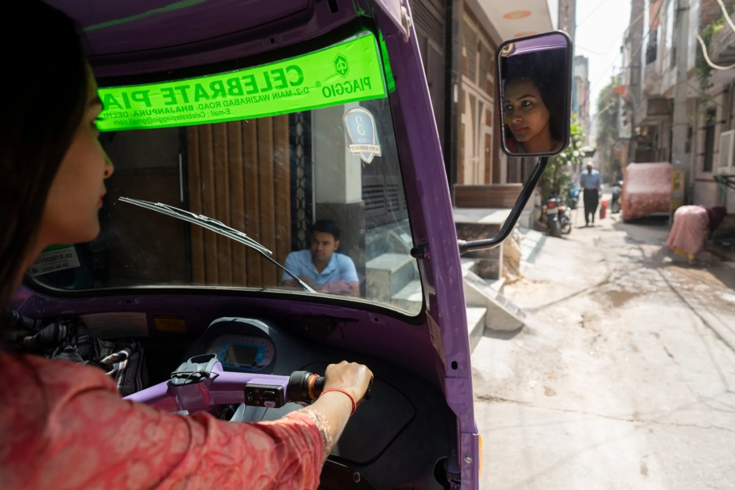 Dolly Maurya poses in an electric auto-rickshaw she purchased using a government subsidy in Delhi, April 25, 2022