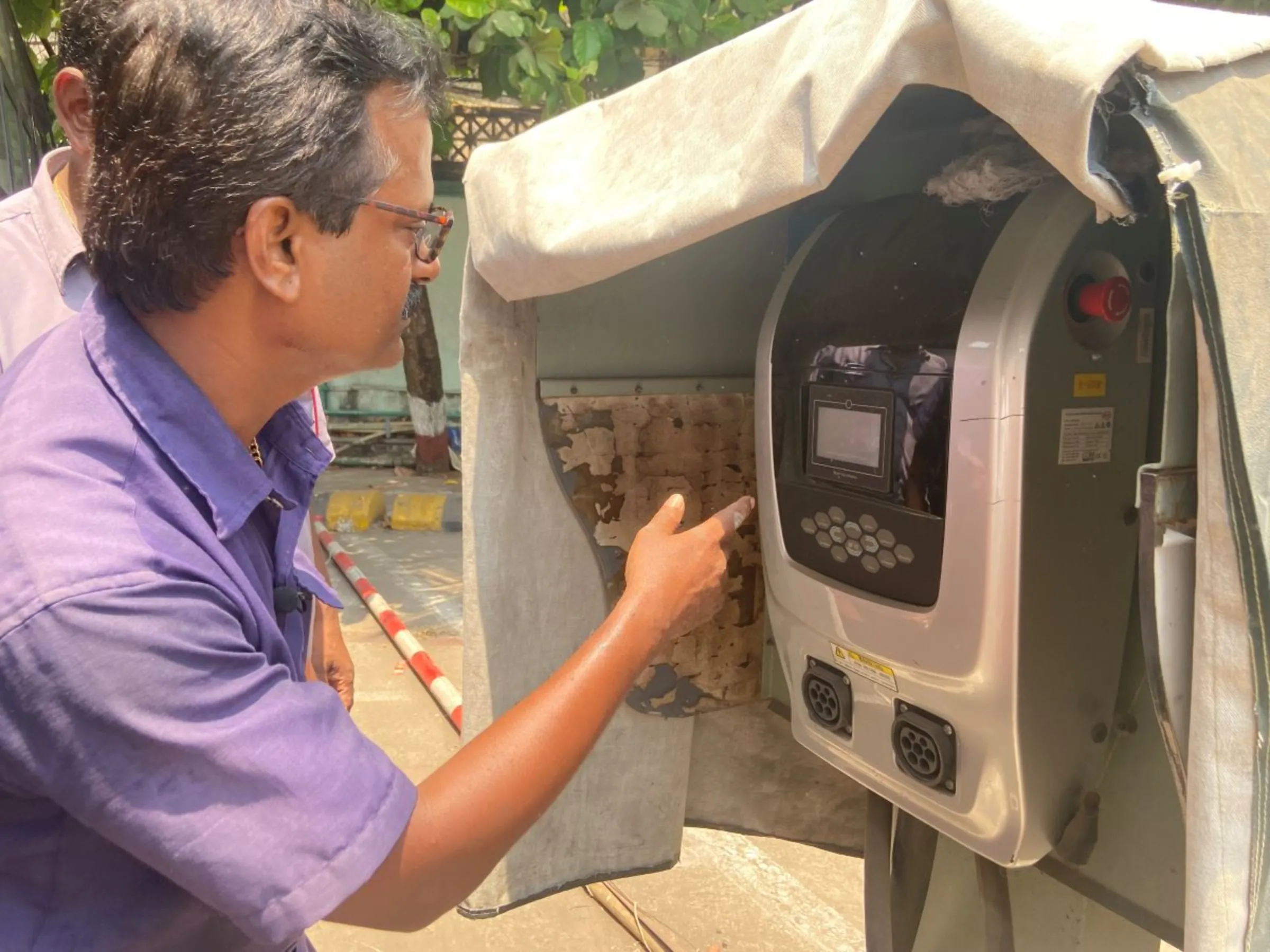 Sanjay Shashikant Kerkar, senior mechanic with Mumbai's public transport body, checks the charging point for electric buses at a depot in Mumbai, India, April 19 2023. Thomson Reuters Foundation/Roli Srivastava