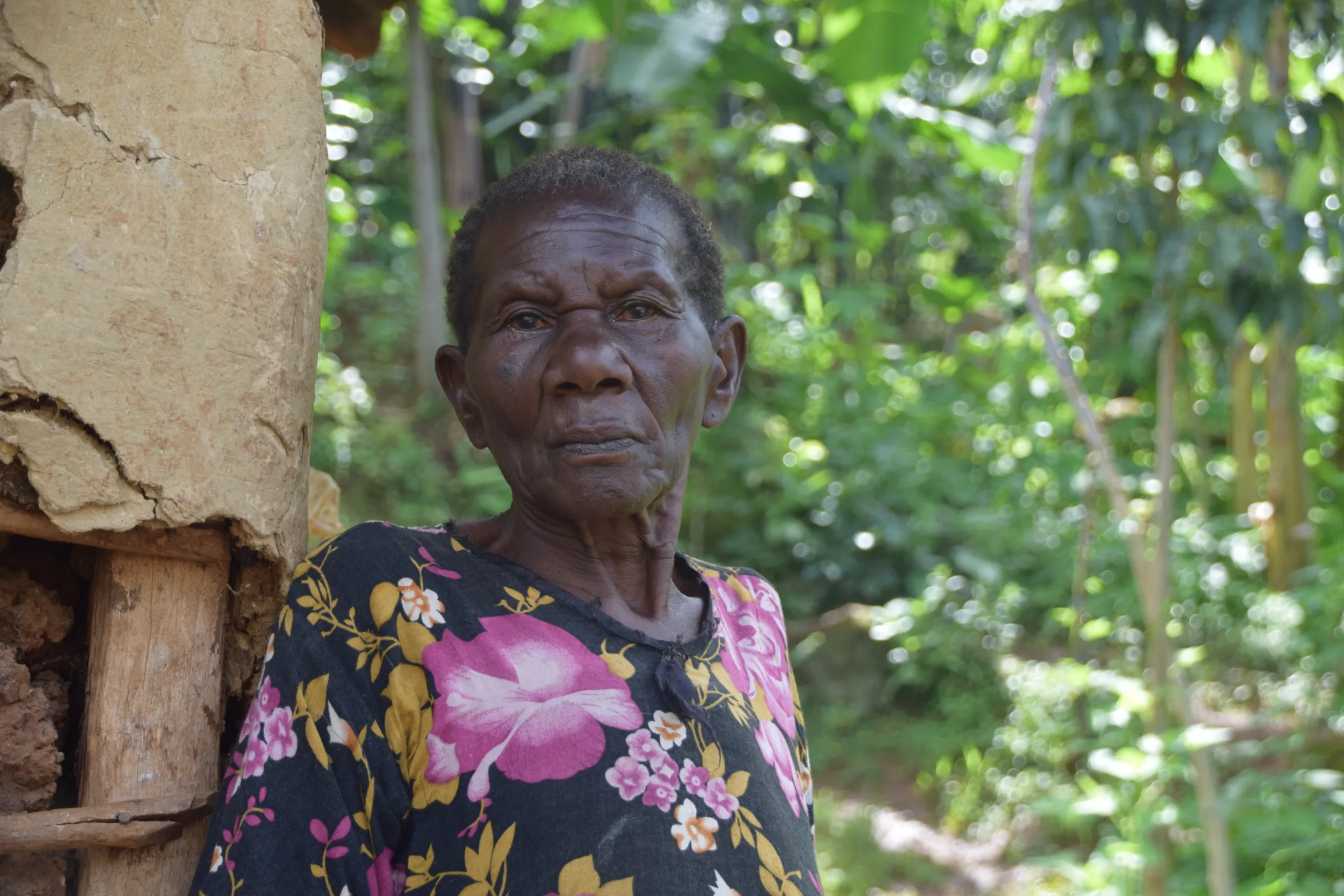 A woman in a flower patterned top stands against a tree