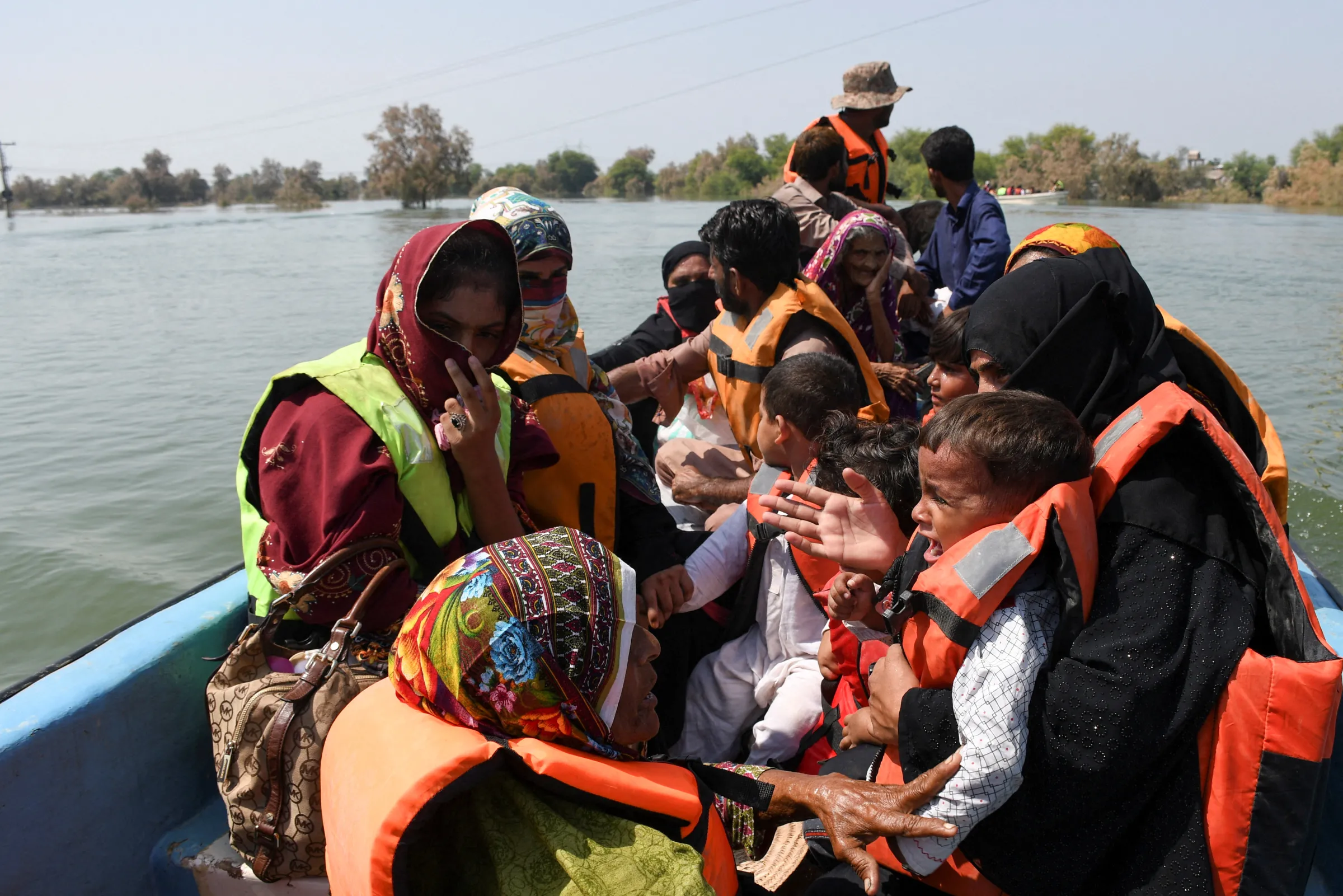 people affected by flooding sit in a boat, following rains and floods during the monsoon season in village Arazi, in Sehwan, Pakistan, September 11, 2022. REUTERS/Yasir Rajput