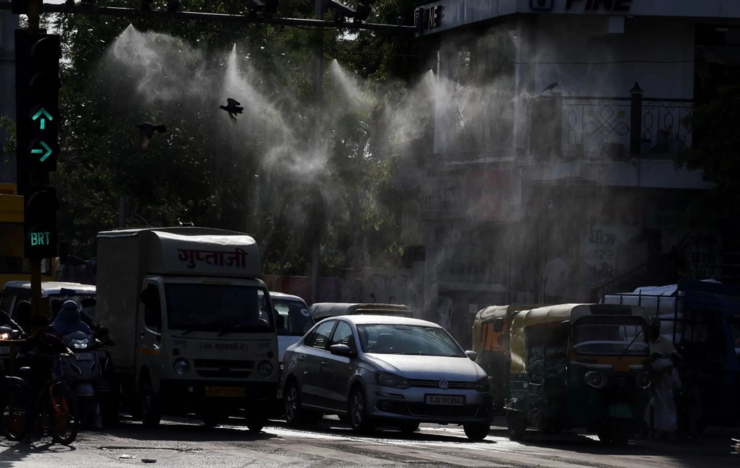 Vehicles wait under a water mist at traffic signals on a hot summer day in Ahmedabad, India, May 9, 2024. REUTERS/Amit Dave