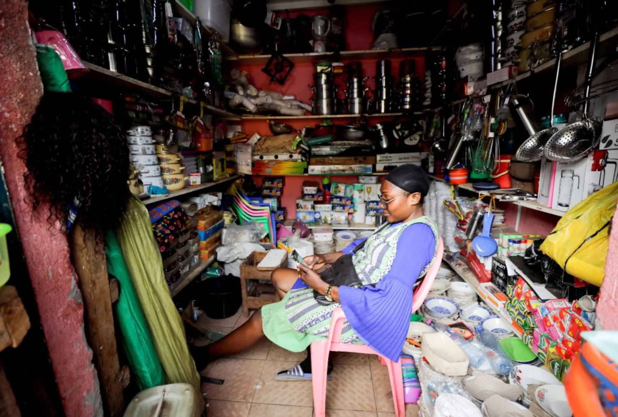 A vendor looks at her phone at the Mvog Ada market in Yaounde, Cameroon, January 29, 2022