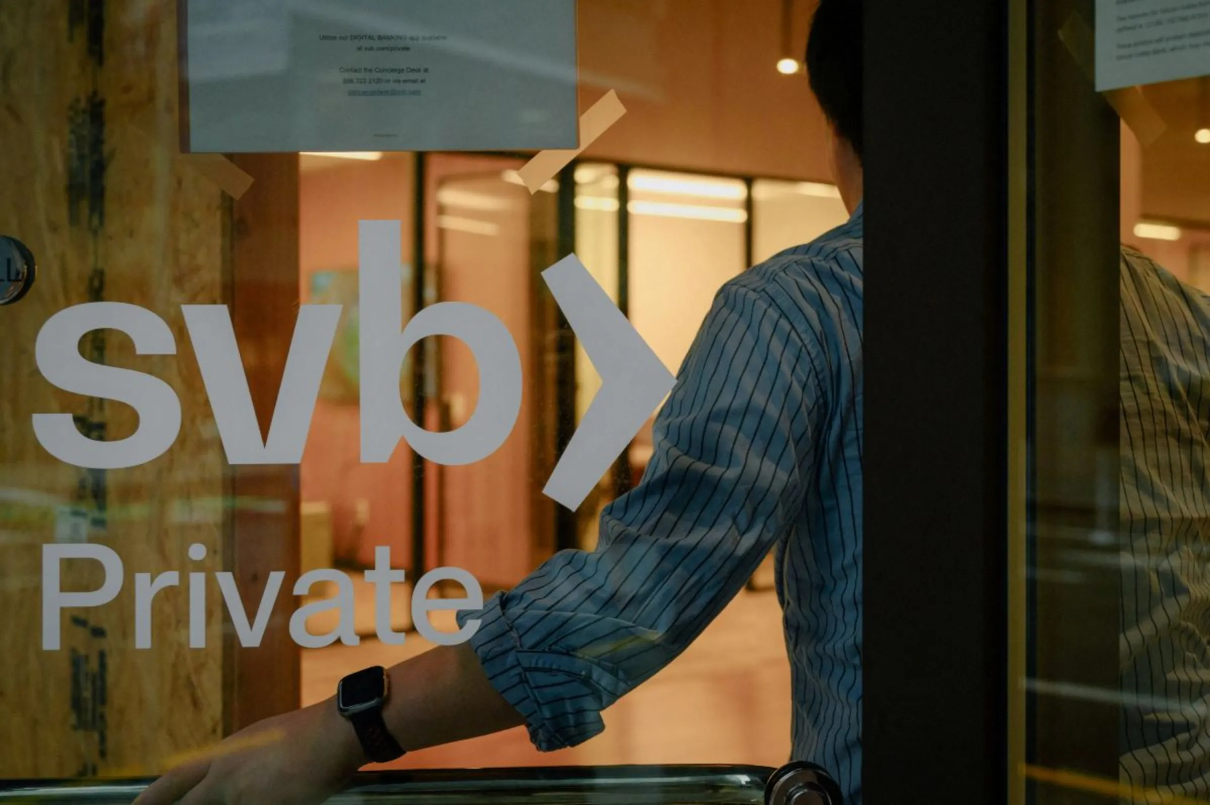 An employee holds the door open at the Silicon Valley Bank branch office in downtown San Francisco, California, U.S., March 13, 2023. REUTERS/Kori Suzuki